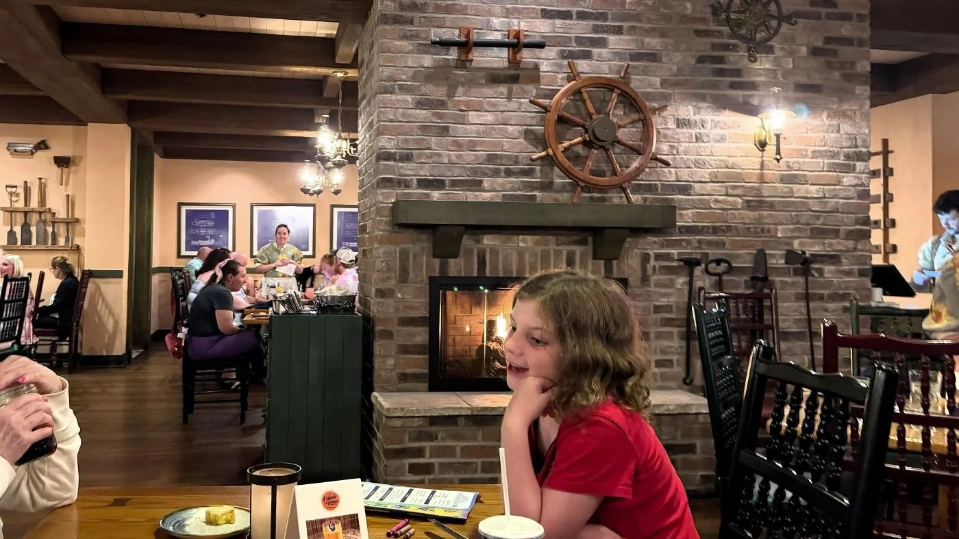 A rustic, Cajun-themed restaurant with a brick fireplace, old farm tools, and heavy wooden chairs.