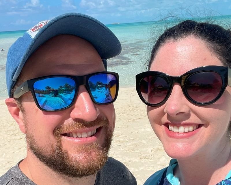 couples selfie with the serenity bay ocean behind them on disney's private island, castaway cay