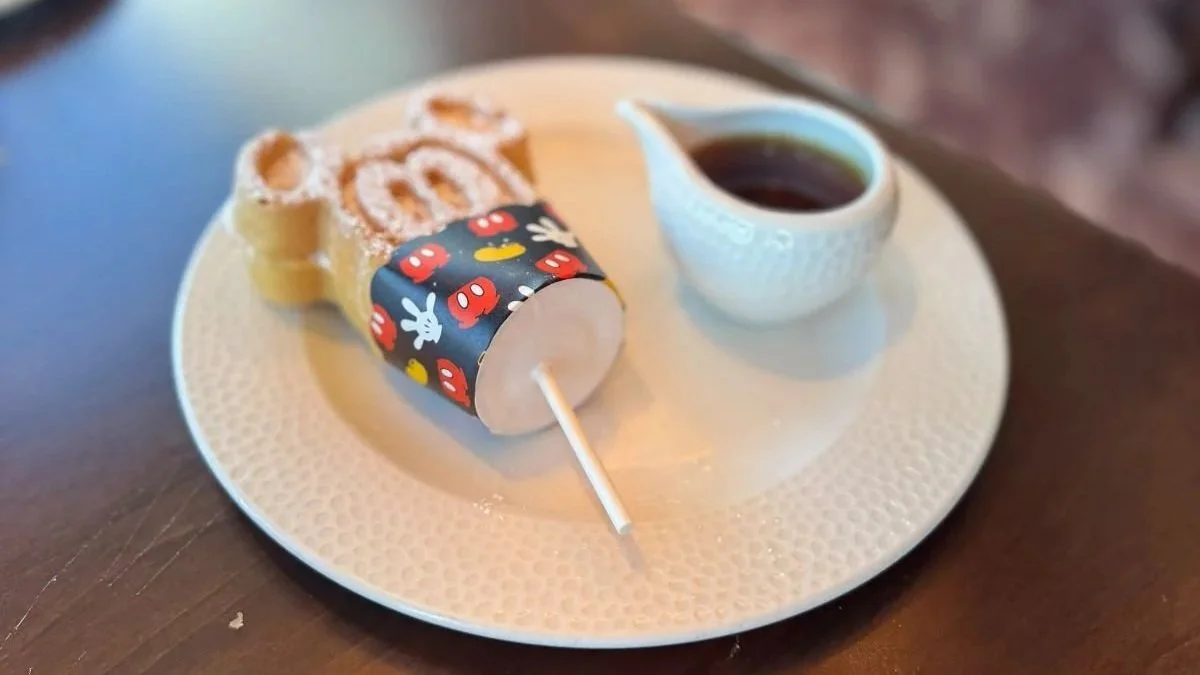 A photo of a Mickey waffle popper at Topolino's character breakfast. It has a popsicle stick attached to a waffle shaped like Mickey Mouse.