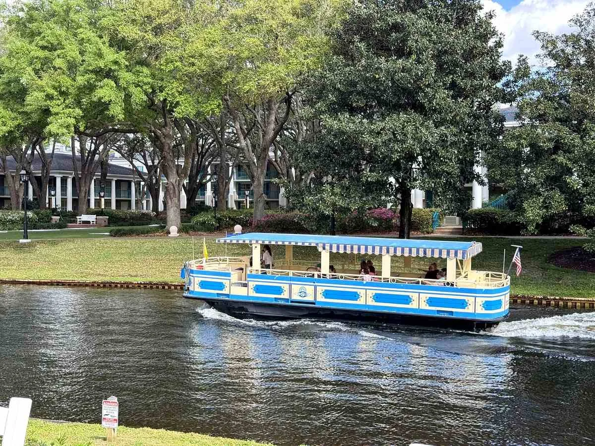 A white and blue boat going in front of the magnolia bend southern mansions. The boat goes from Disney Springs to Port Orleans Riverside, a moderate disney resort.