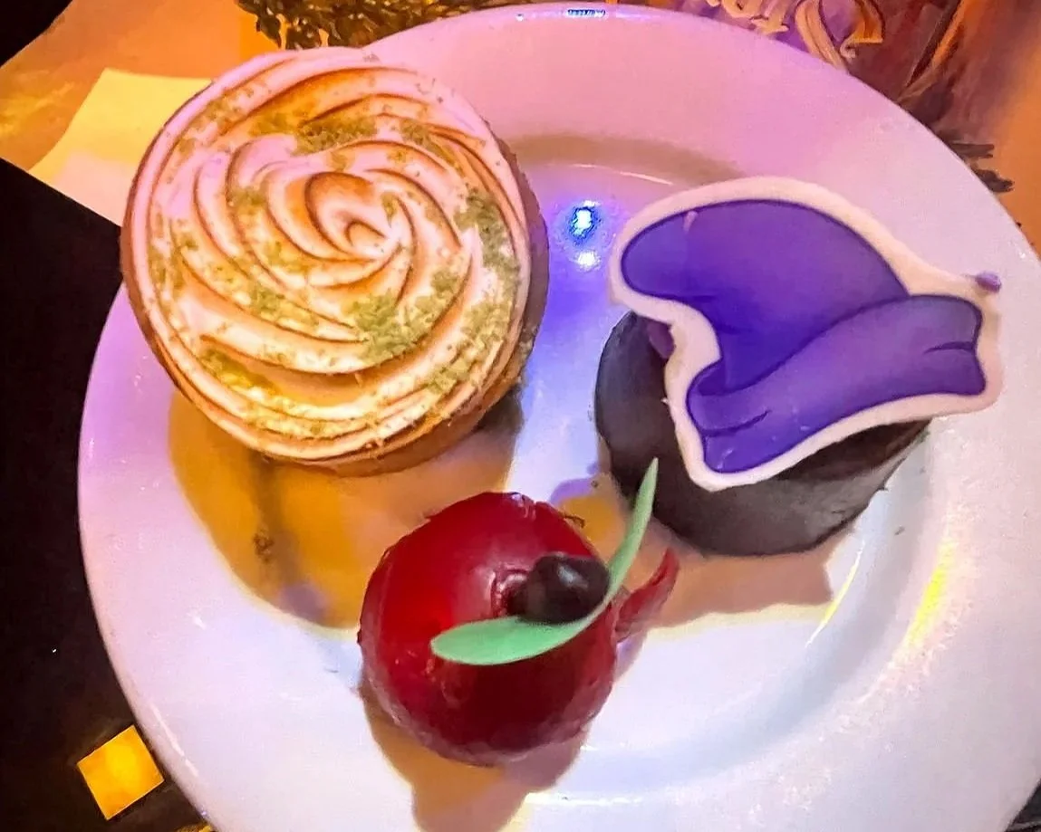 Three intricately designed desserts, including a "poison apple" on a plate. They are from Story Book Dining at Artist Point, a character meal at Disney World.