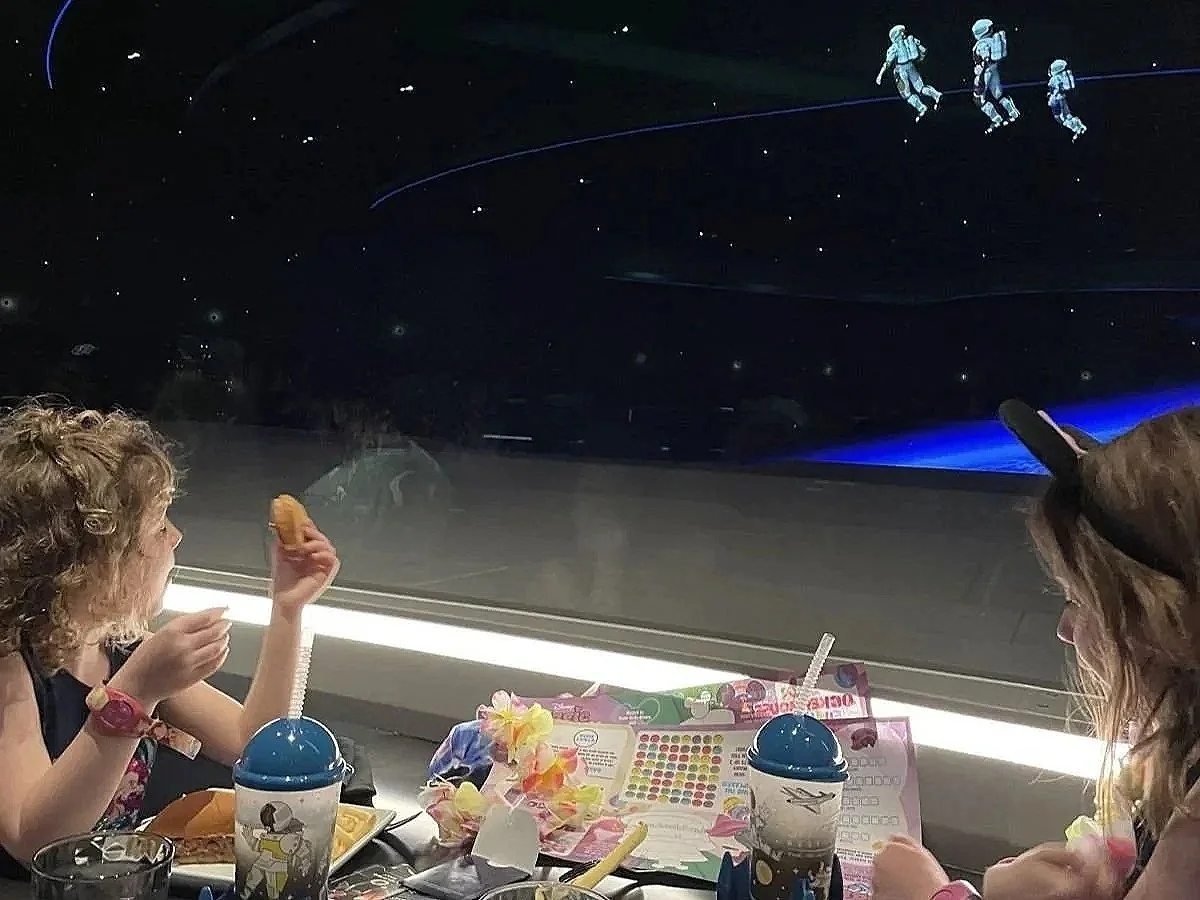 Two girls eating and watching astronauts go by at Space 220 in EPCOT at Disney World. A great Disney World restaurant for kids.