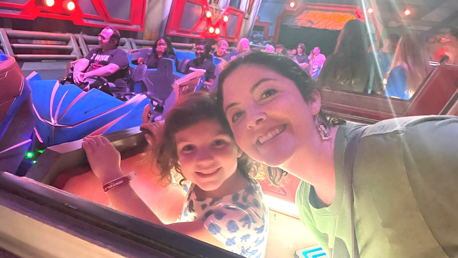 A mother in daughter pause for a picture in next in line for guardians of the galaxy: cosmic rewind at epcot in Disney World during an EPCOT After Hours event. You can see the blue and gold roller coaster in the background.