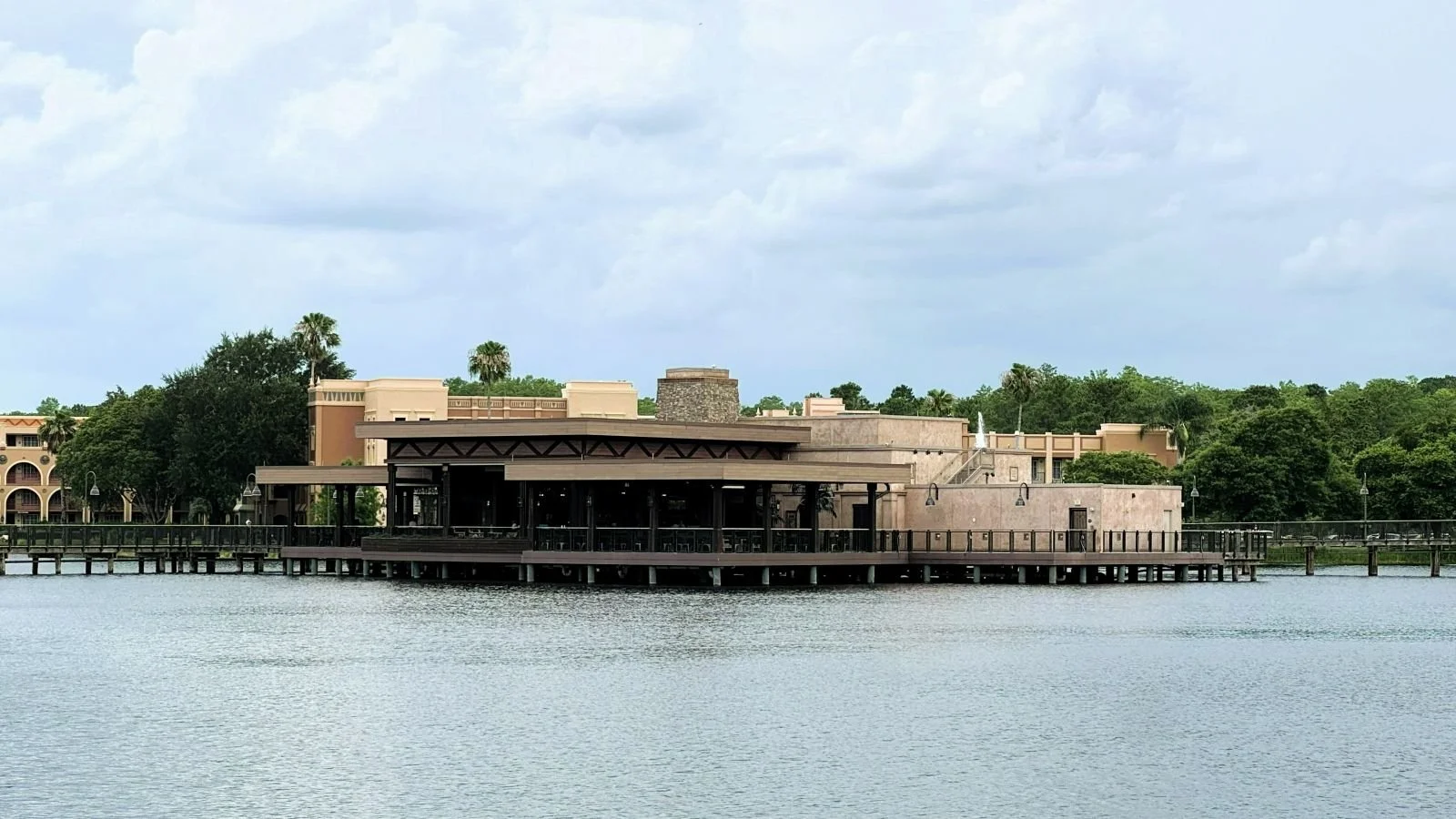 An image of the three bridges restaurant at coronado springs resort in Disney World, a moderate resort. You can see the outdoor seating across a lake with several bridges leading to it. It sit in the middle of the lake.