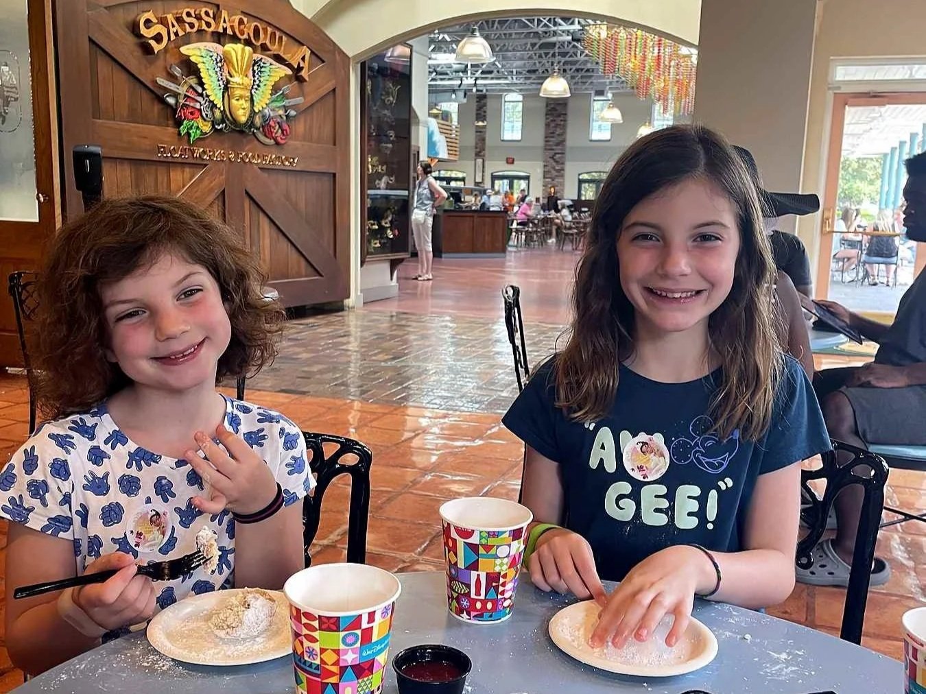 Two girls enjoying beignets at Scat Cat Club cafe in the lobby of Port Orleans French Quarter.