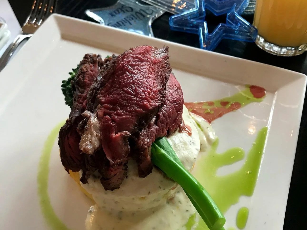 Several slices of medium rare steak on asparagus and mashed potatoes, an entree for breakfast at Cinderella's Royal Table, a character meal at Disney World. There's a souvenir magic wand in the background.