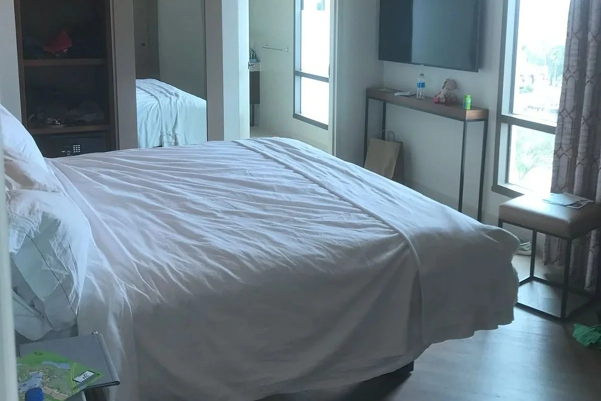 Image of a bedroom in a gran destino deluxe suite. A king bed leads to a large bathroom. Tv on the wall.