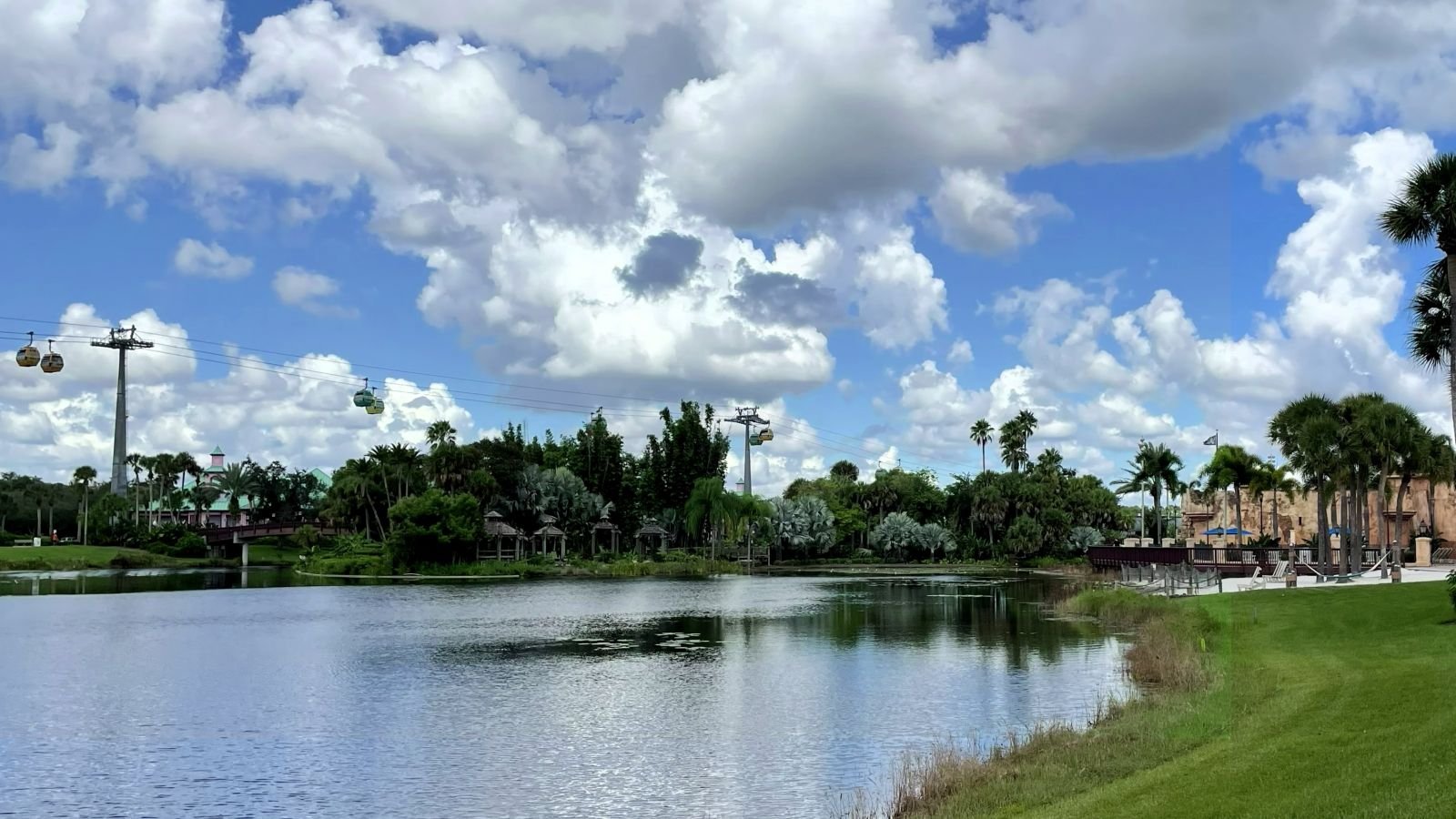 A view from the sidewalk at caribbean beach resort in Disney World. You can see a lake, the Spanish fortress pool, and the Skyliner in the distance at this moderate resort.