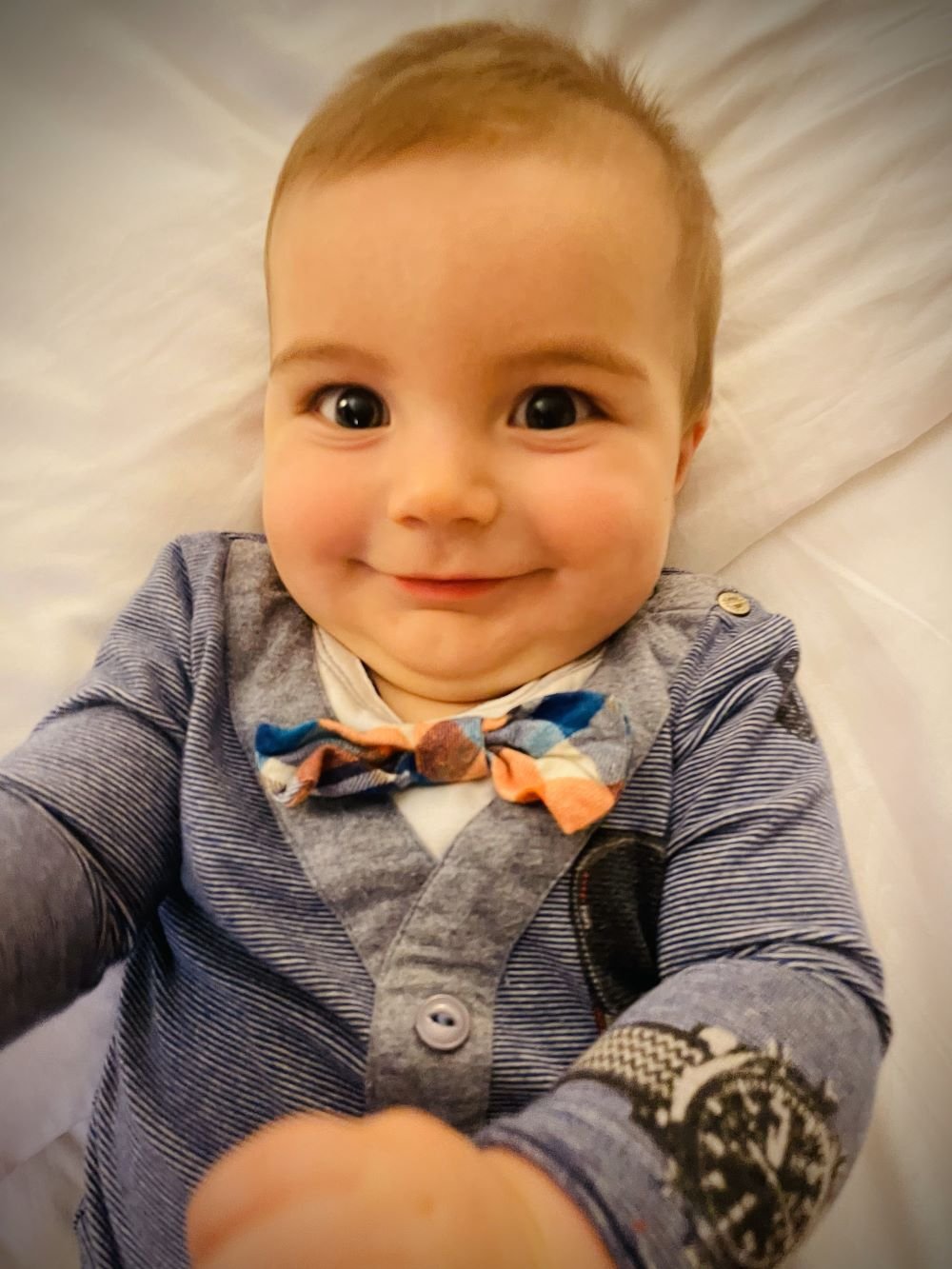 A baby wearing a onesie that looks like it has a bowtie, sunglasses, and watch. Toddler on a Disney Cruise.