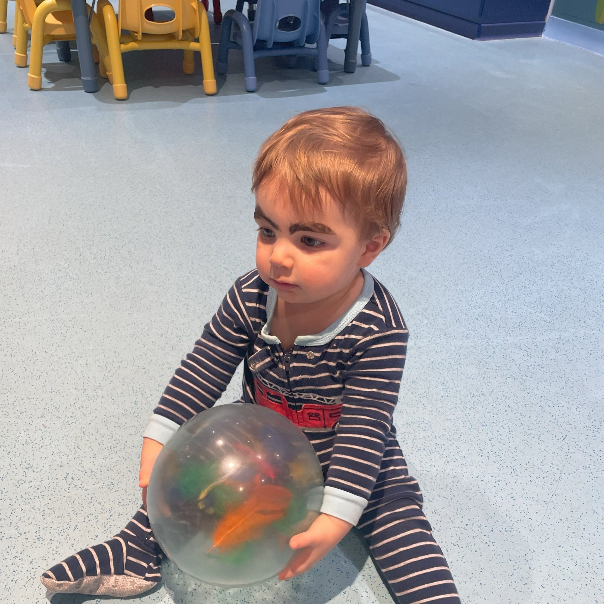 A baby plays with a ball at the disney magic it's a small world nursery