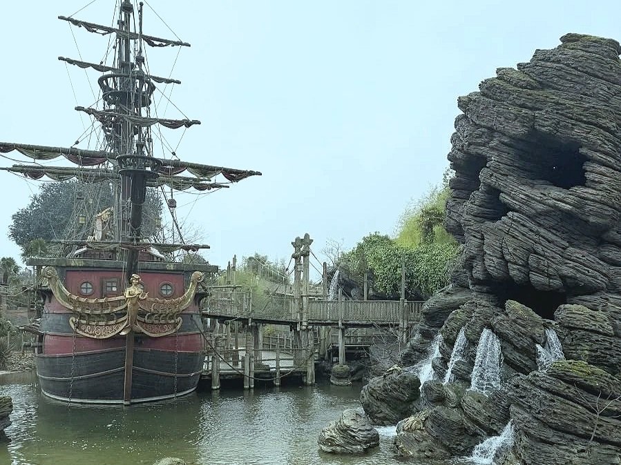 A picture of skull rock (a rock formation shaped like a skull) and a red and black galleon pirate ship. Both are explorable areas in Disneyland Paris.