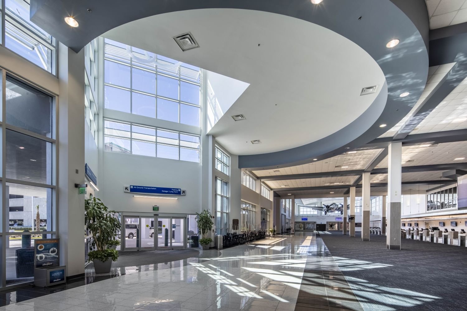 A photo of Sanford Orlando International Airport. It's entrance of the airport with high ceilings and a lighting effect marking out a rotunda. The ticket counters for the airport are to the right, and the passenger drop off to the left.