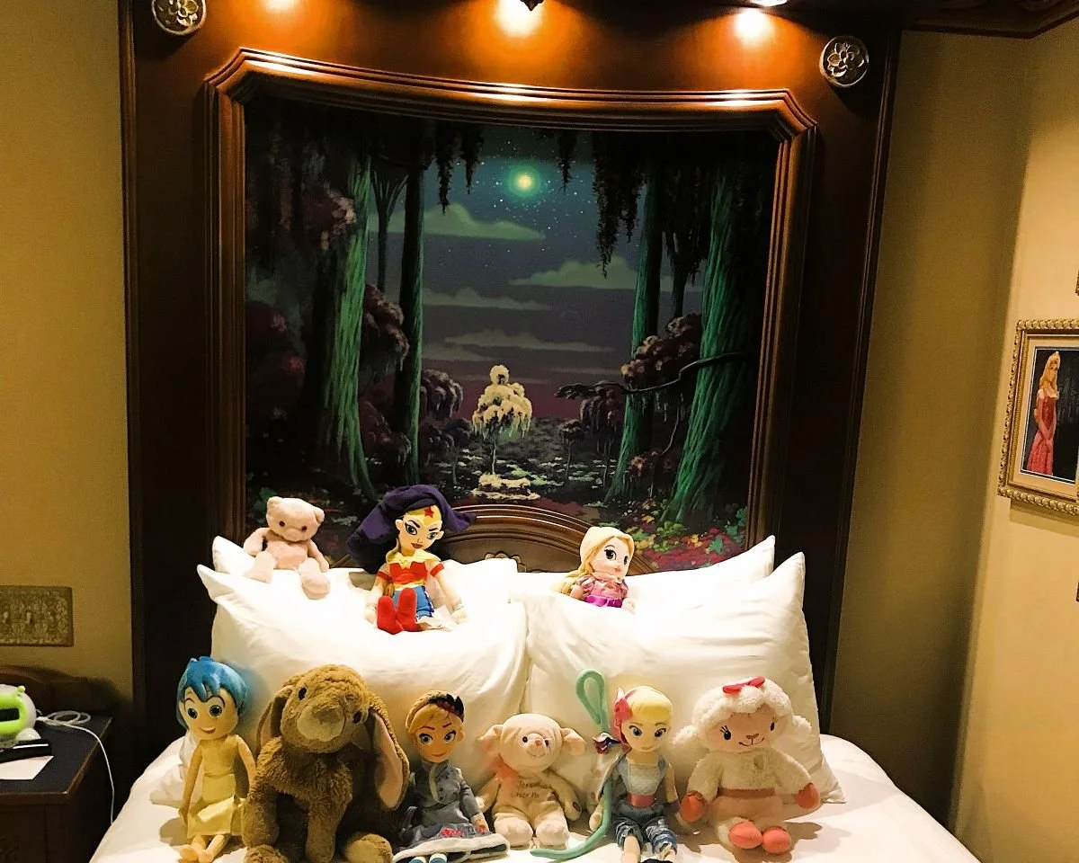 Stuffed animals are neatly arranged in front of intricate headboard in one of the Royal Guest Rooms at Port Orleans Riverside, a moderate resort in Disney World.