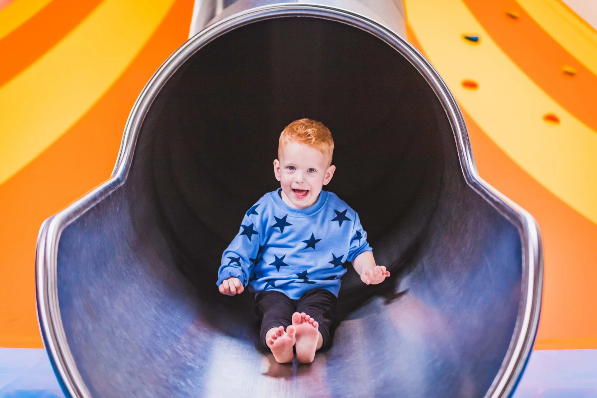 Child coming out of a slide laughing in a playground.