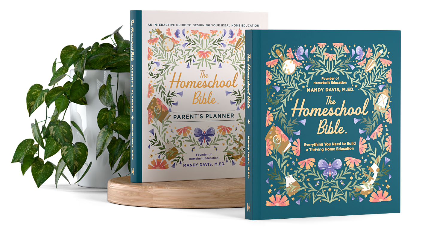 Two books titled "The Homeschool Bible" by Mandy Davis, M.Ed., with one being a Parent's Planner. They are displayed on a wooden surface with a potted plant beside them.