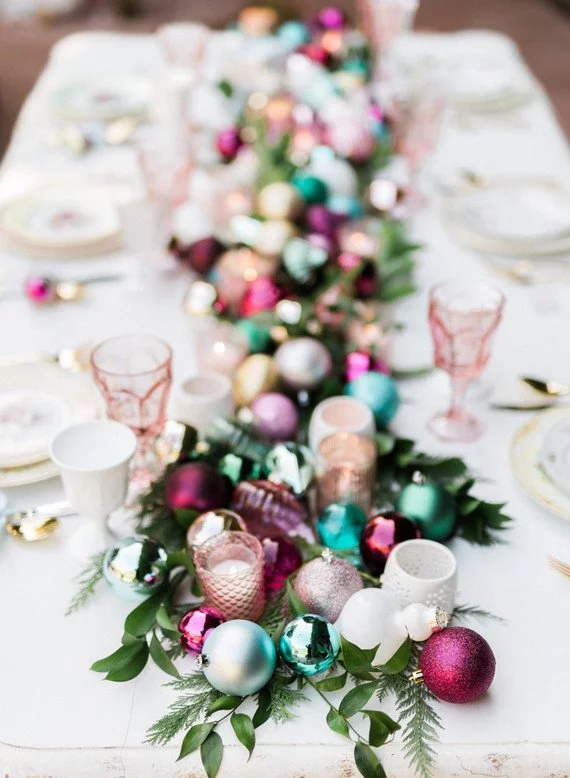 Colourful votive holders and tree ornaments set on a green garland, bringing the tree to the table. Photographer: Jennifer Fujikawa Photography Design: Seven Stems