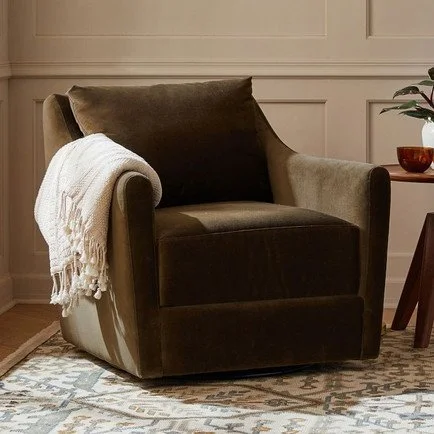 Olive brown velvet swivel armchair with a deep cushioned seat, curved arms, and tailored upholstery, styled with a cream throw in a warm traditional living room.
