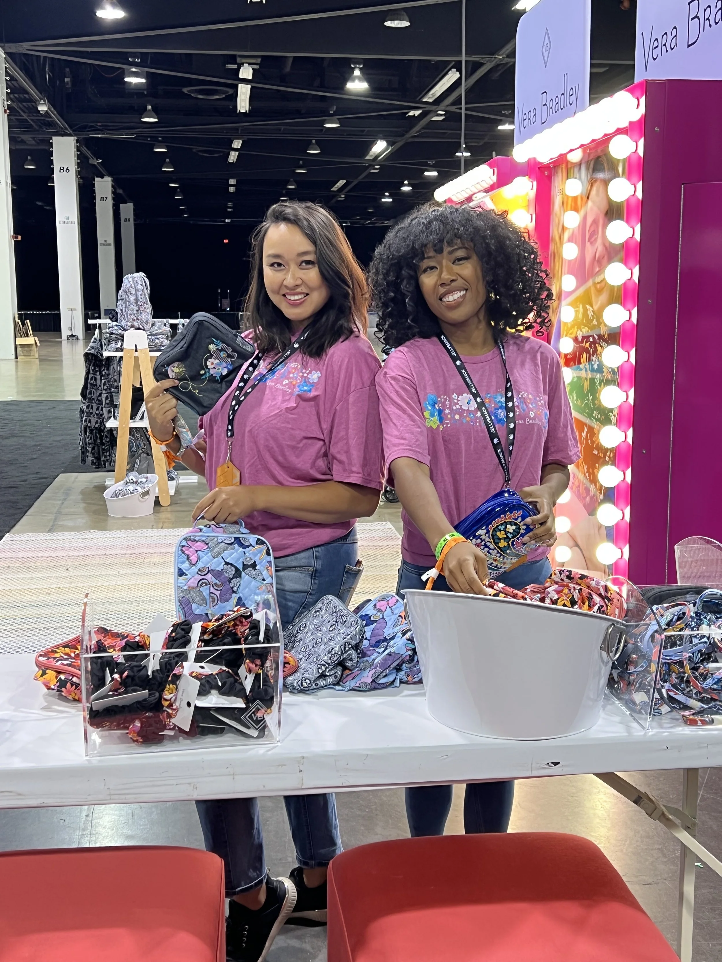 Vera Bradley brand ambassadors and event staff in pink t-shirts displaying products at a promotional booth exhibition - Encore Nationwide