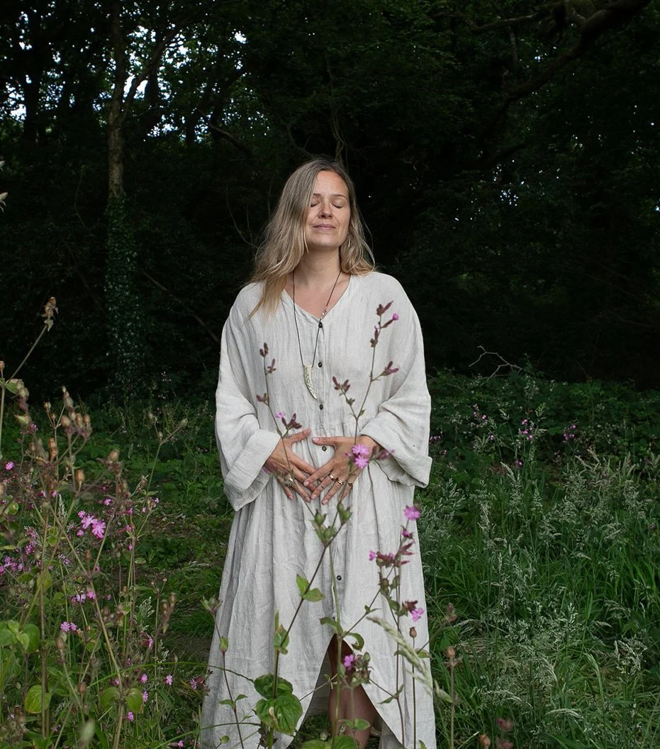 Katie Rose standing in a woodland wearing a light dress.