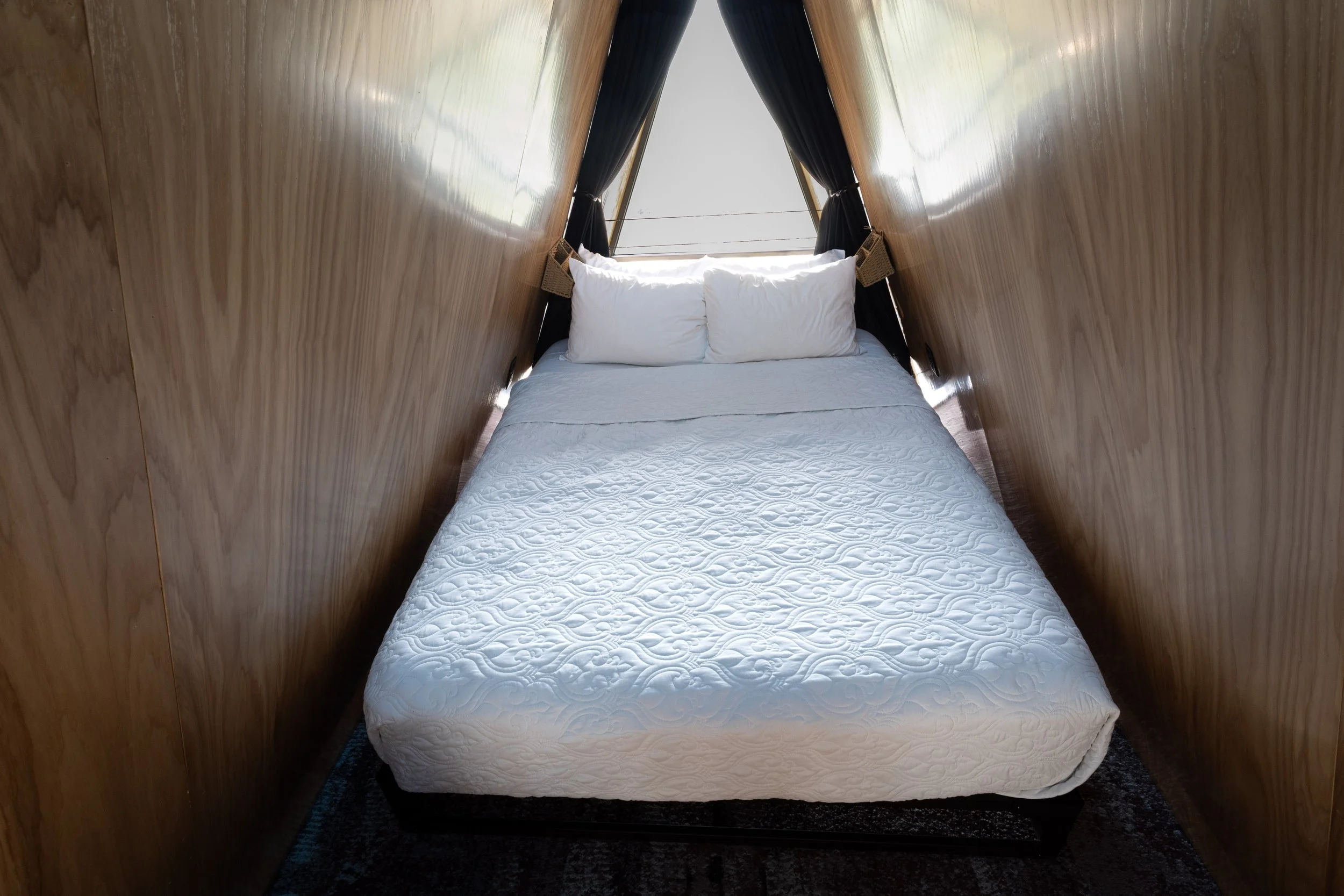 Cozy bed inside A-frame cabin loft with wood walls and window view in the Black Hills near Lead South Dakota