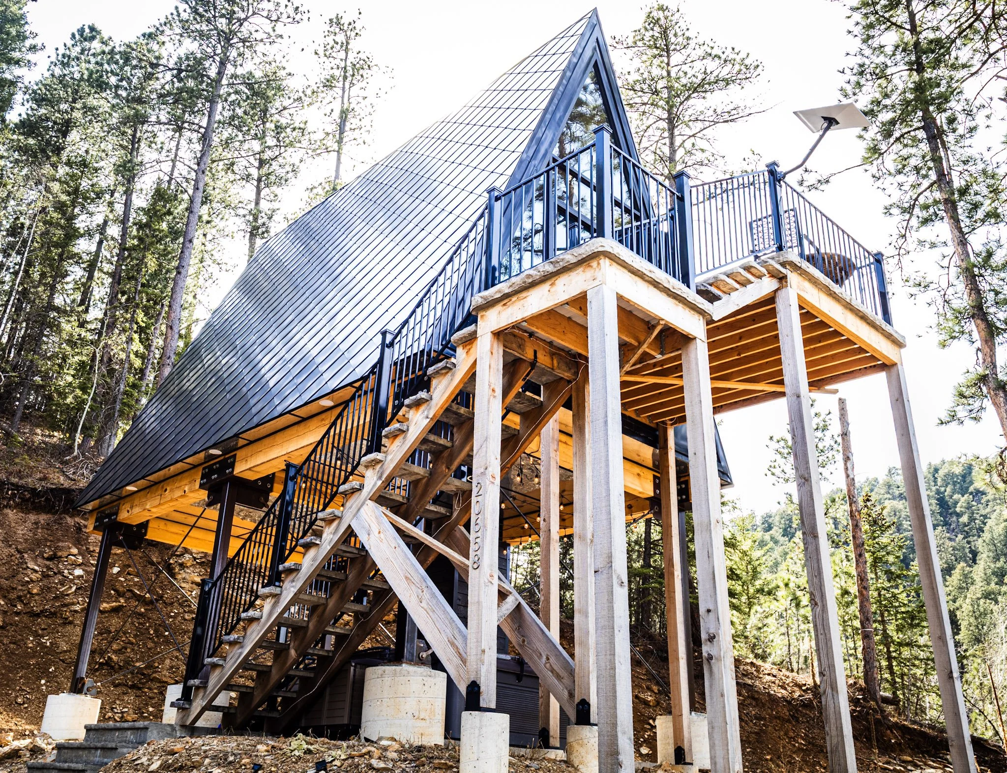 Black Steel Pines Cabin A-frame vacation rental in Lead South Dakota with elevated deck and forest surroundings