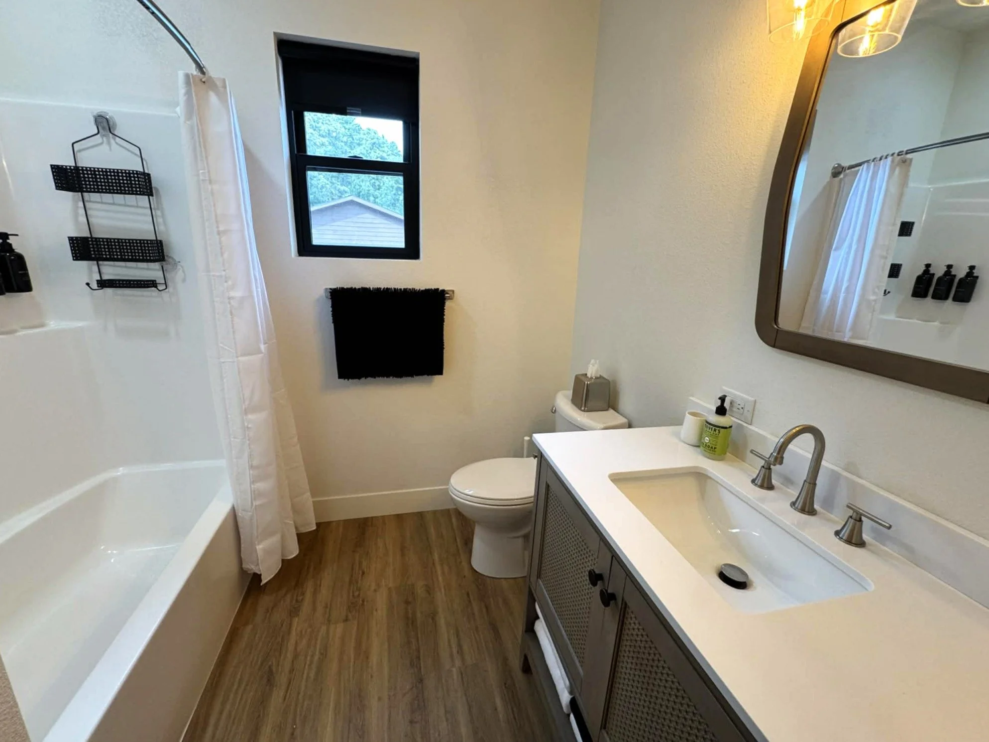 Clean modern bathroom with vanity and tub shower at The Overlook on Mountain View Black Hills vacation home
