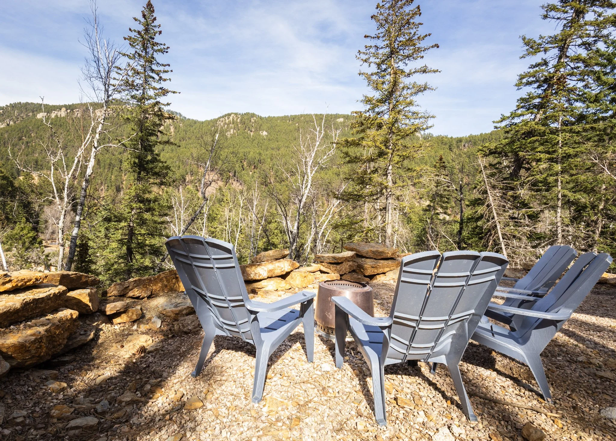 Black Steel Pines Cabin fire pit area with Adirondack chairs overlooking Black Hills forest near Lead South Dakota