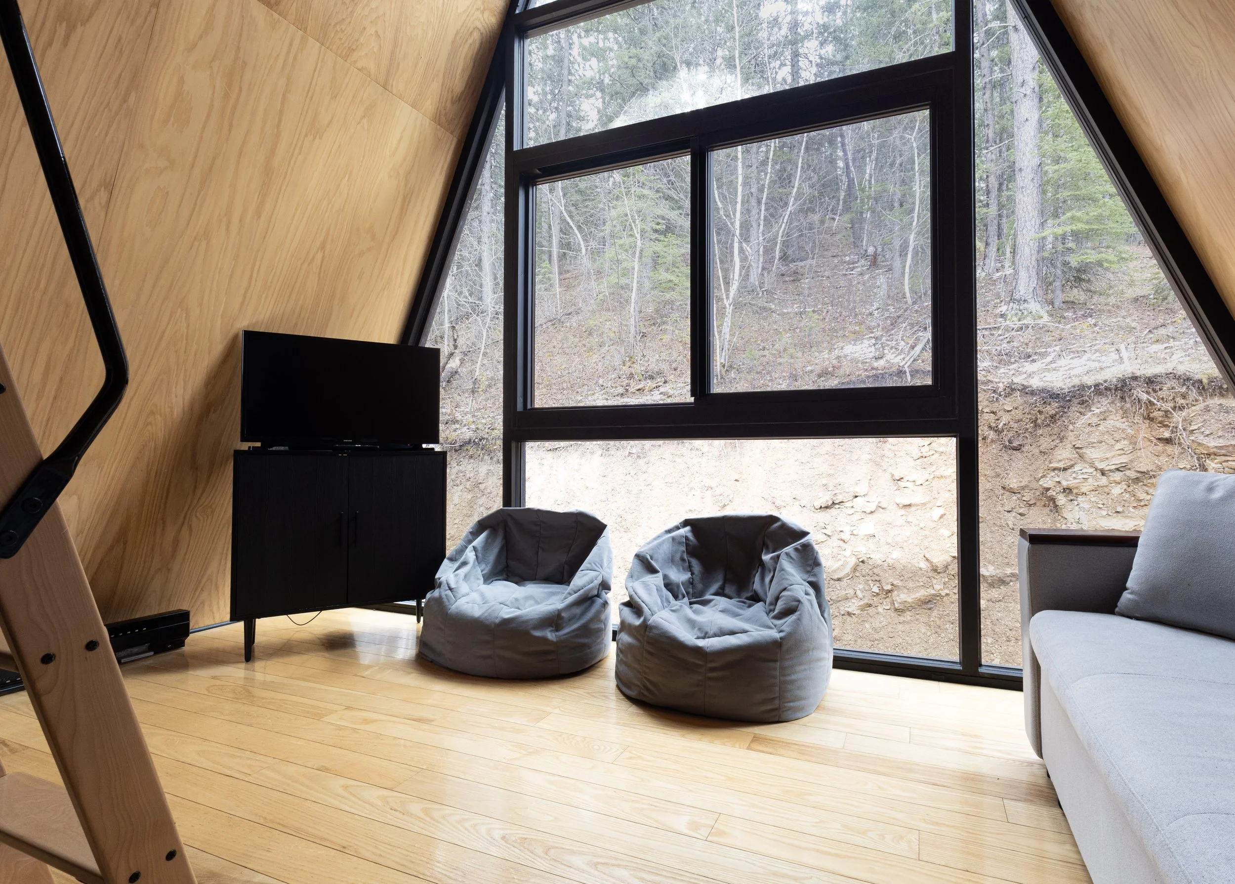 Black Steel Pines Cabin living area with floor-to-ceiling windows and forest views in Lead South Dakota