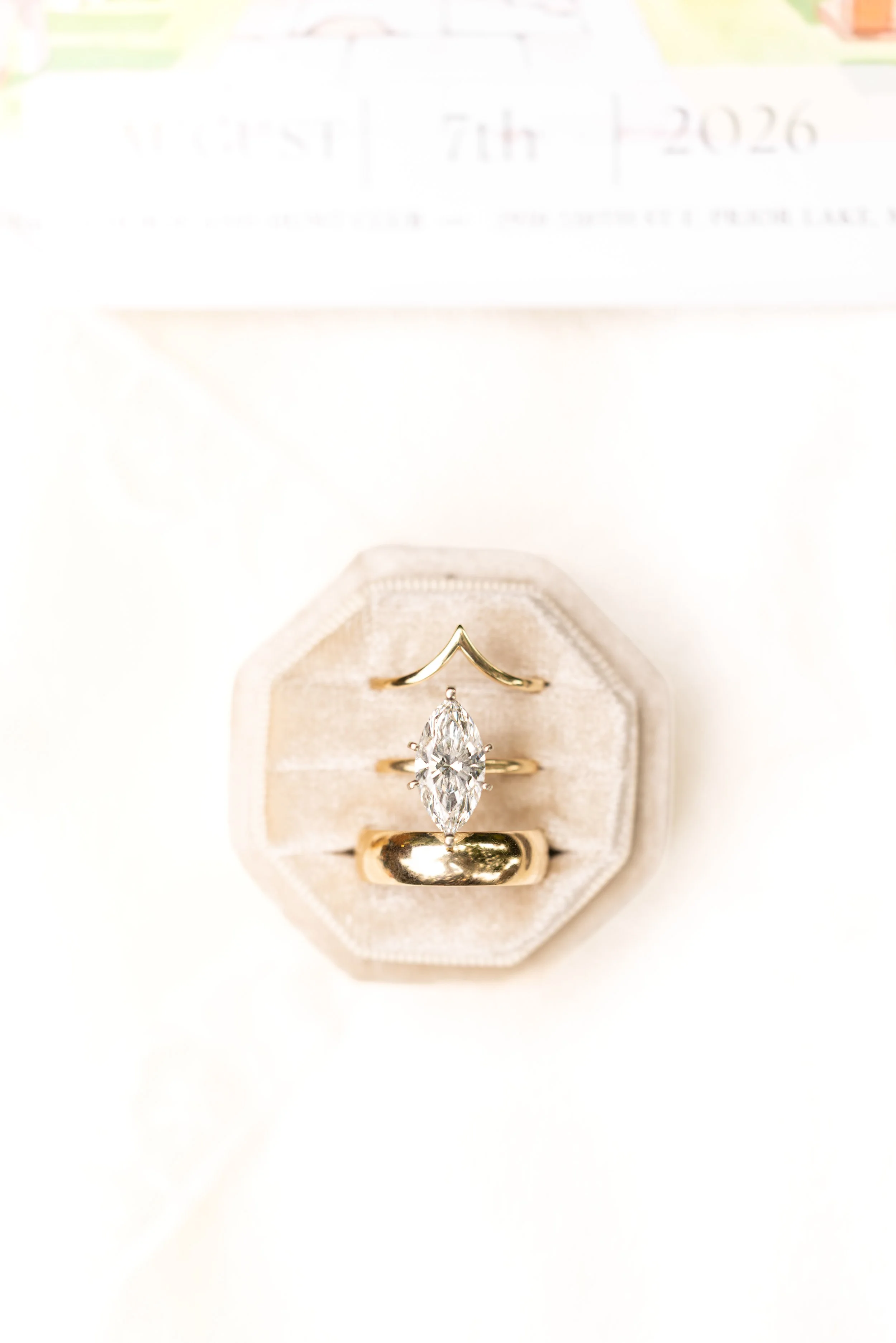 Close-up of a diamond engagement ring in a jewelry box, with a gold band and a large marquise-cut diamond, on a white background.
