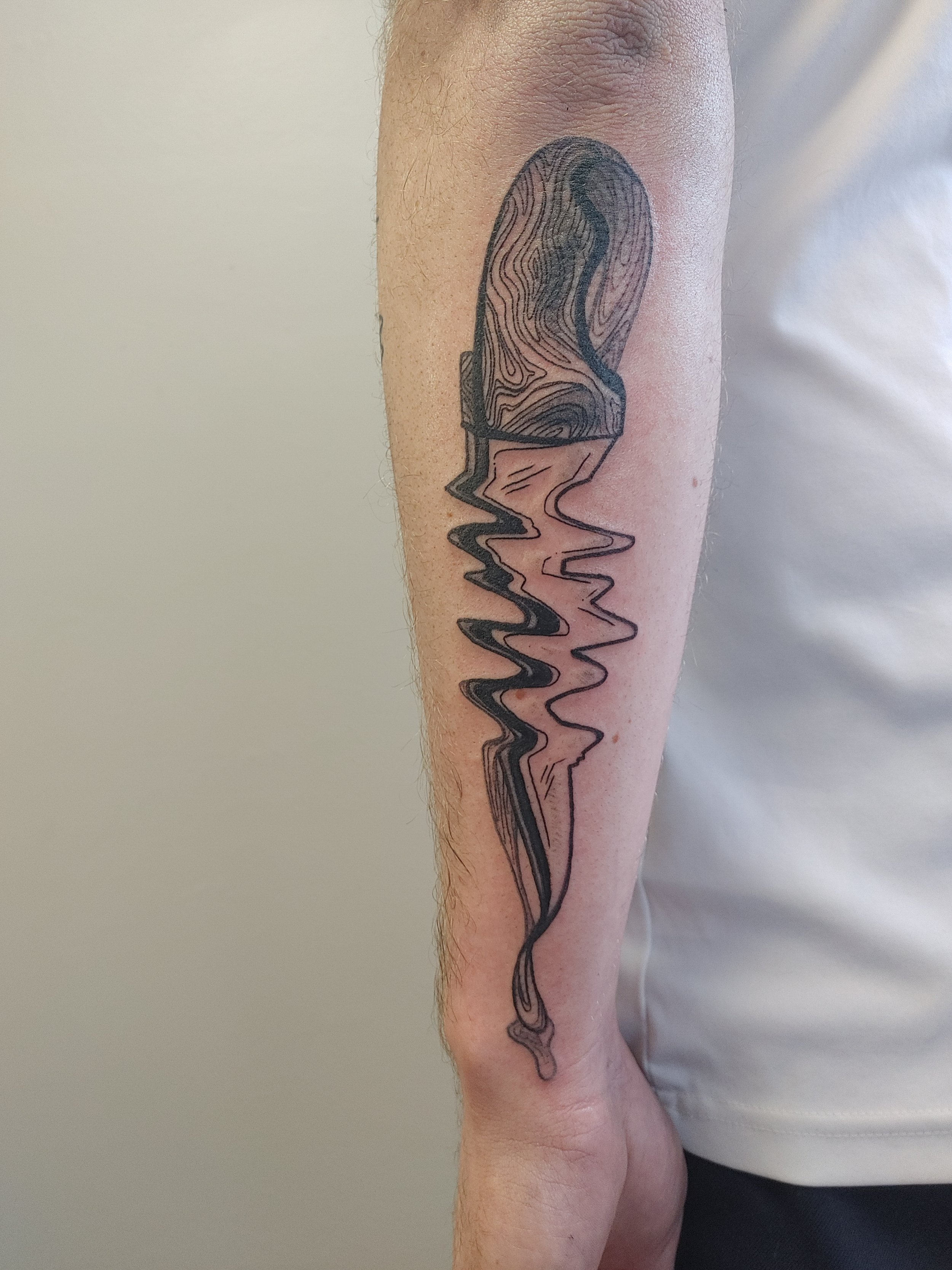 Tattoo of a melting ice cream cone on a person's forearm.