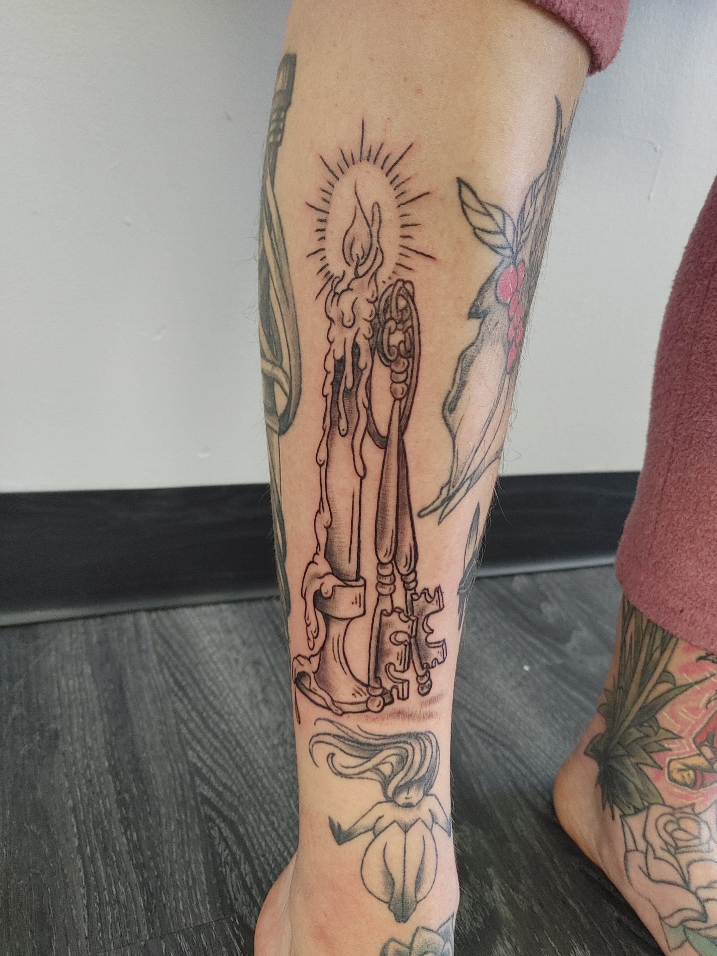 Black outline tattoo of a human digestive system running down the person's leg, with a small flame inside a circle near the top.