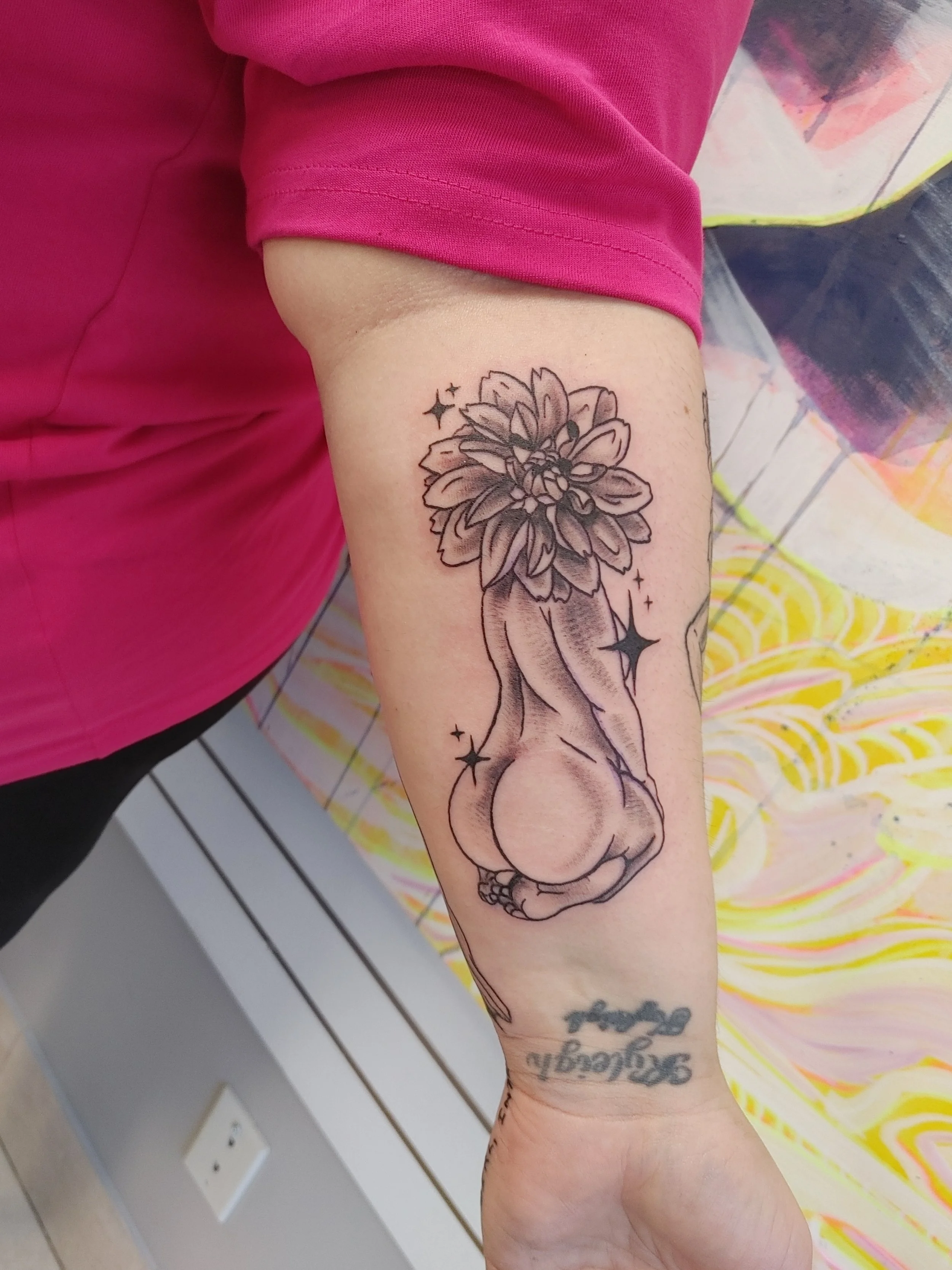 A tattoo of a flower with multiple petals and a skull at the base of the flower on a person's forearm.