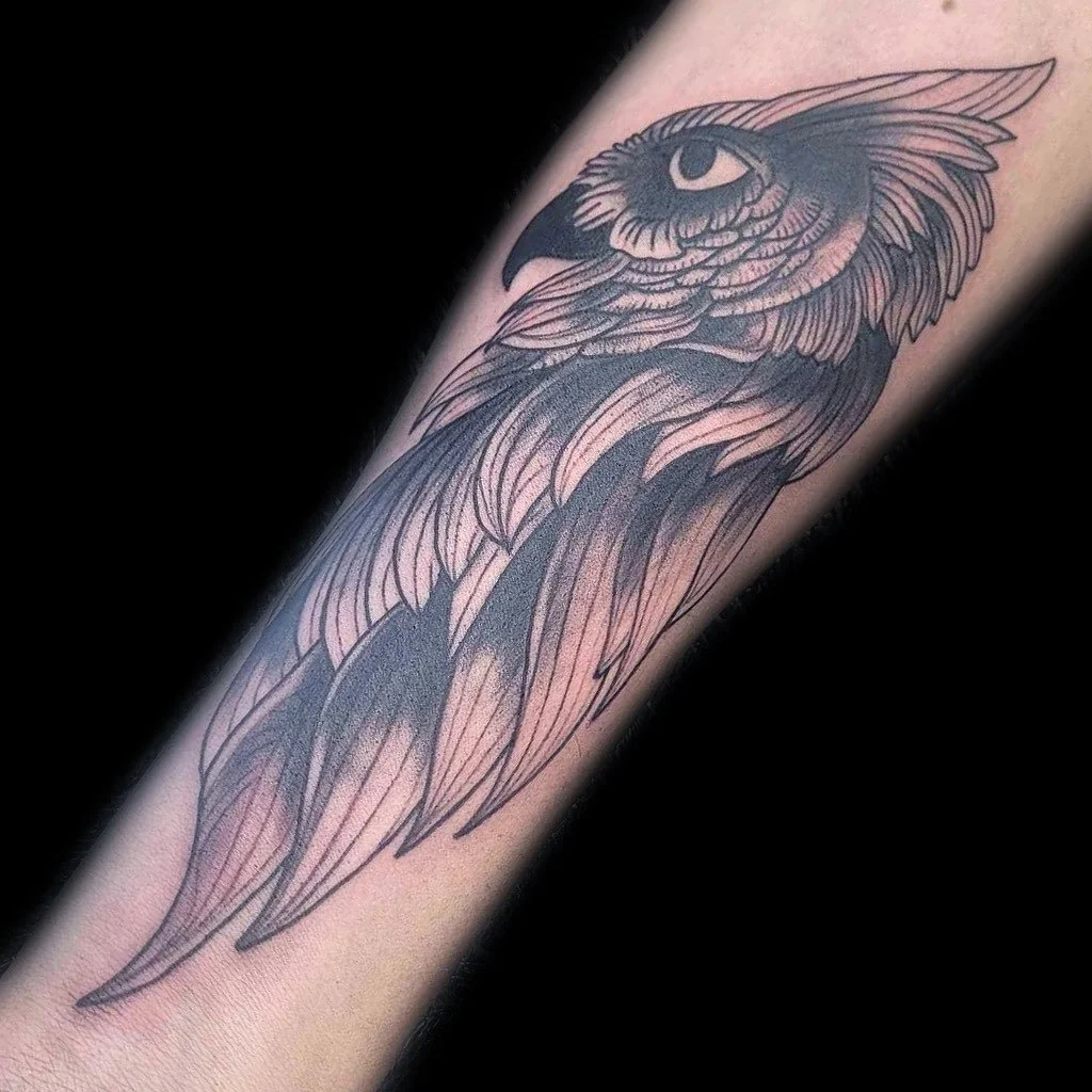 Black and gray tattoo of an eagle's head and wings on a person's arm.
