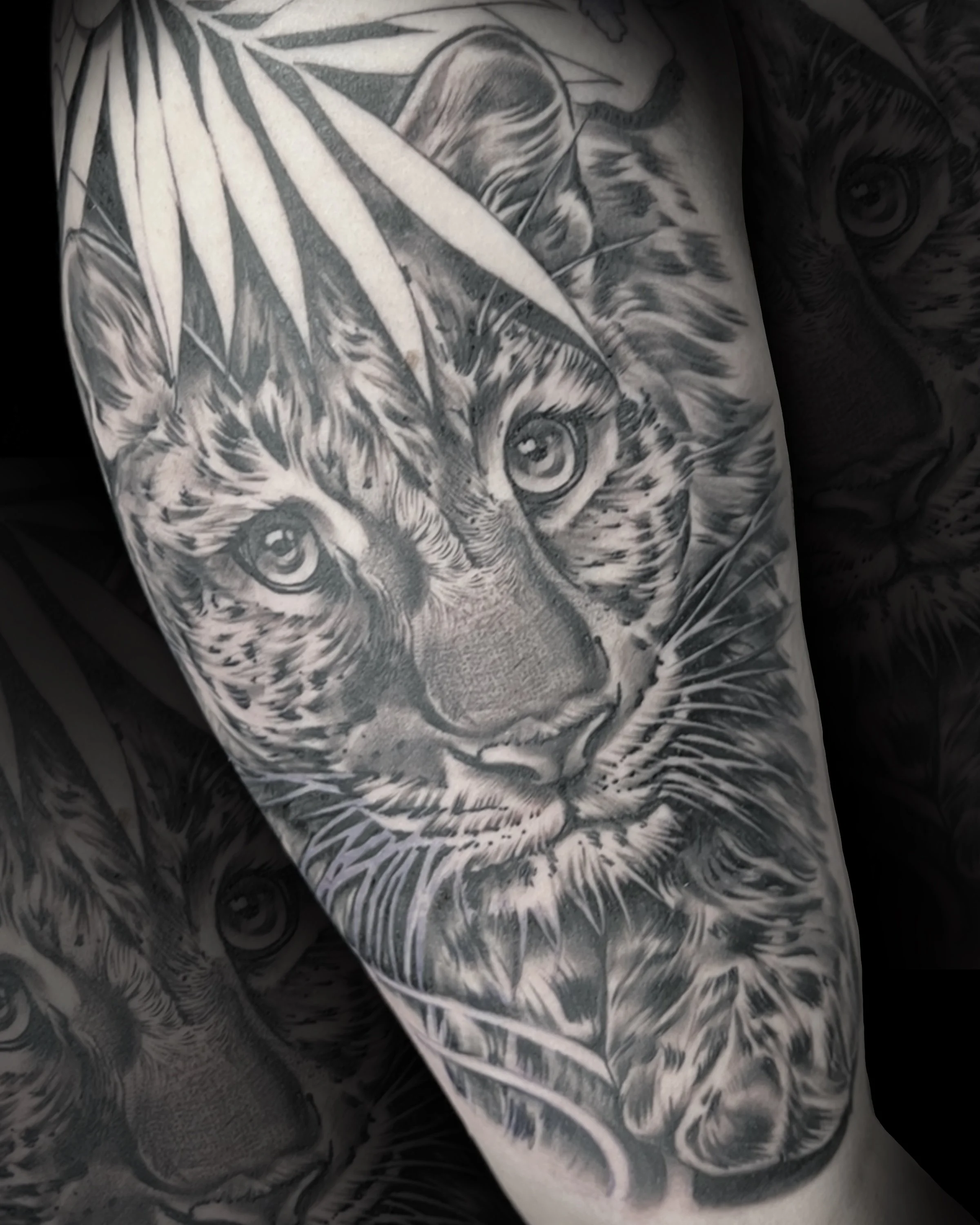 Black and grey tattoo of a leopards face surrounded by leaves. Edmonton tattoo artist, Edmonton Tattoo shop owner