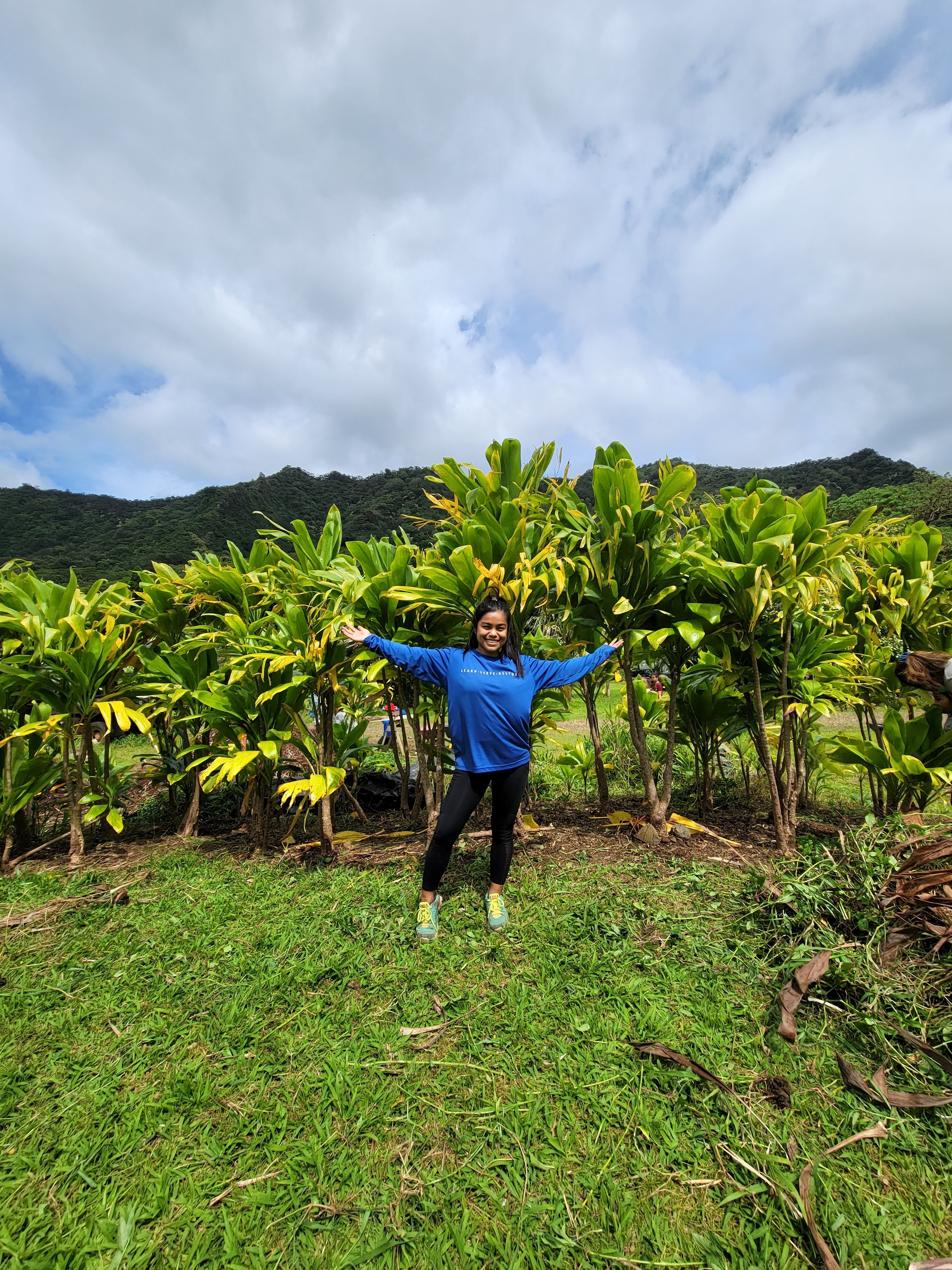 Participant of Environmental Education Leaders Program happily standing in a grove of ti leaf plants.