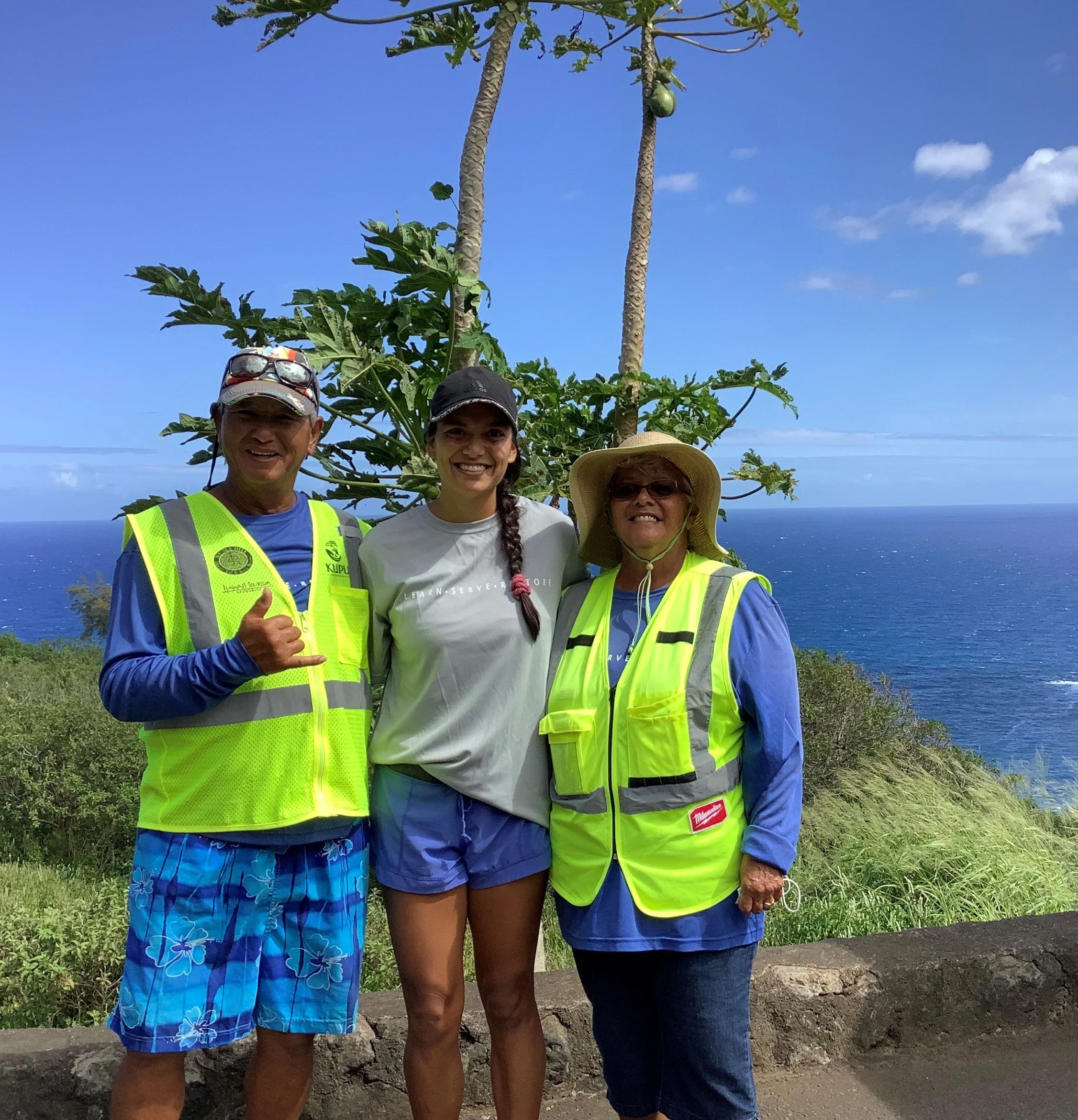 Kupu participant and two volunteers pose for group photo at trailhead.