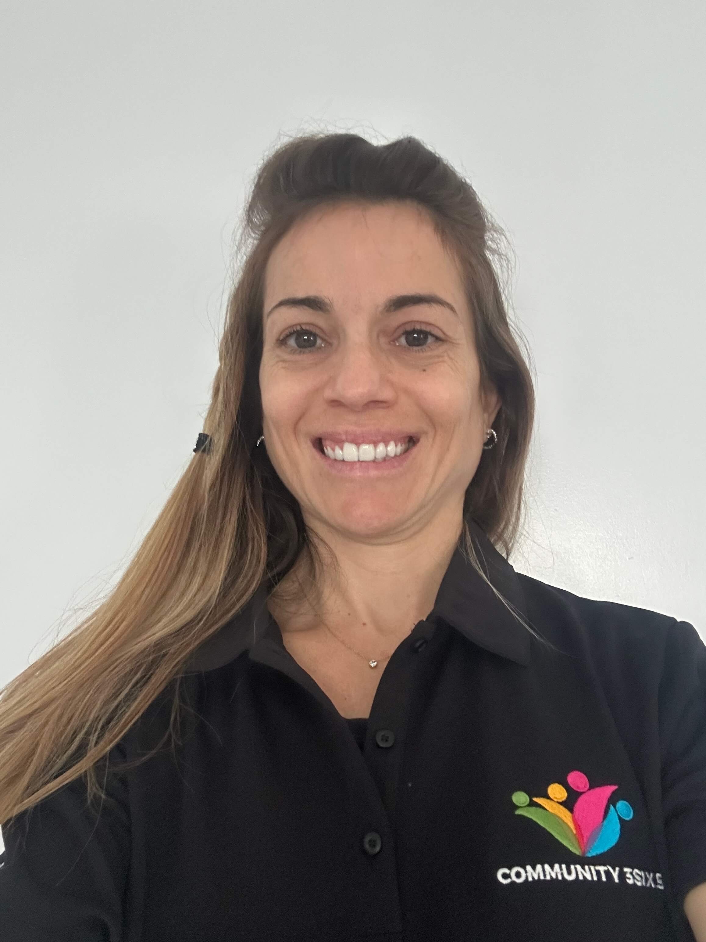 Mariana wearing a black polo uniform shirt and smiling warmly, presenting a friendly and professional appearance.