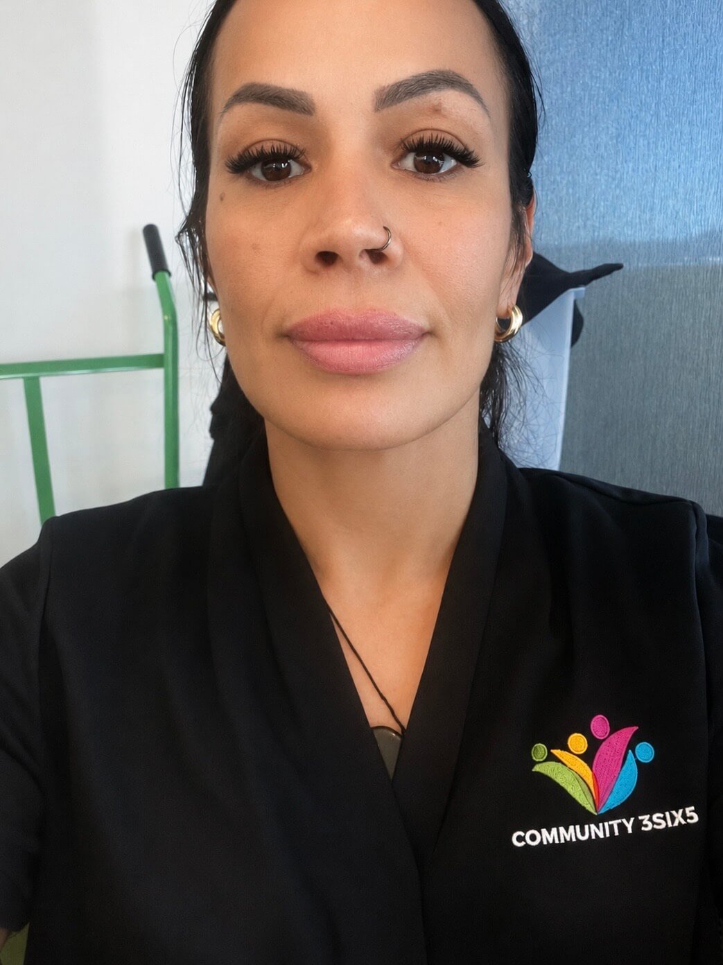 Female staff member Jamie has black hair tied back and is wearing a black uniform polo shirt