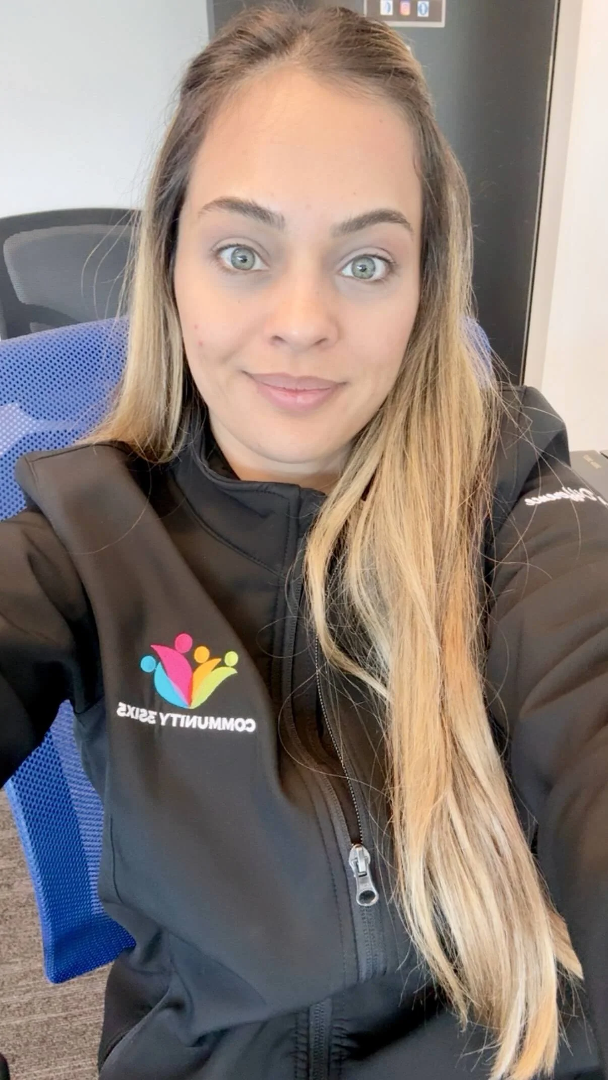Female staff member Larissa has long, straight blonde hair and is wearing a black uniform jacket