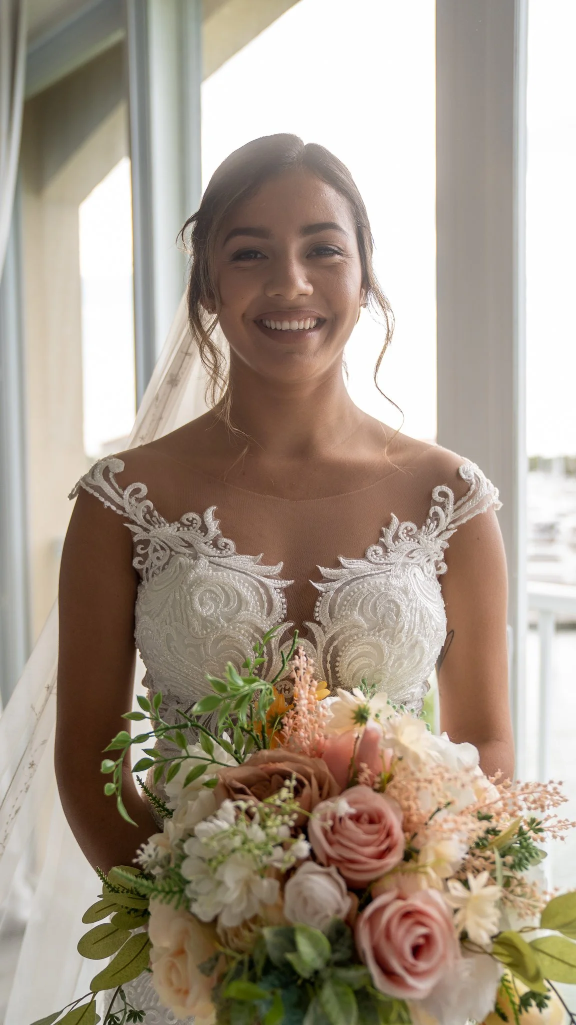 Bride smiling with bouquet during her wedding day portraits. 