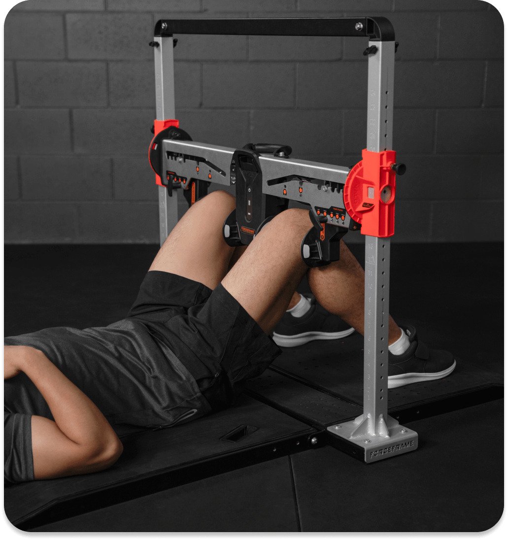 Person lying on a fitness bench using a force frame resistance training device for leg exercises.