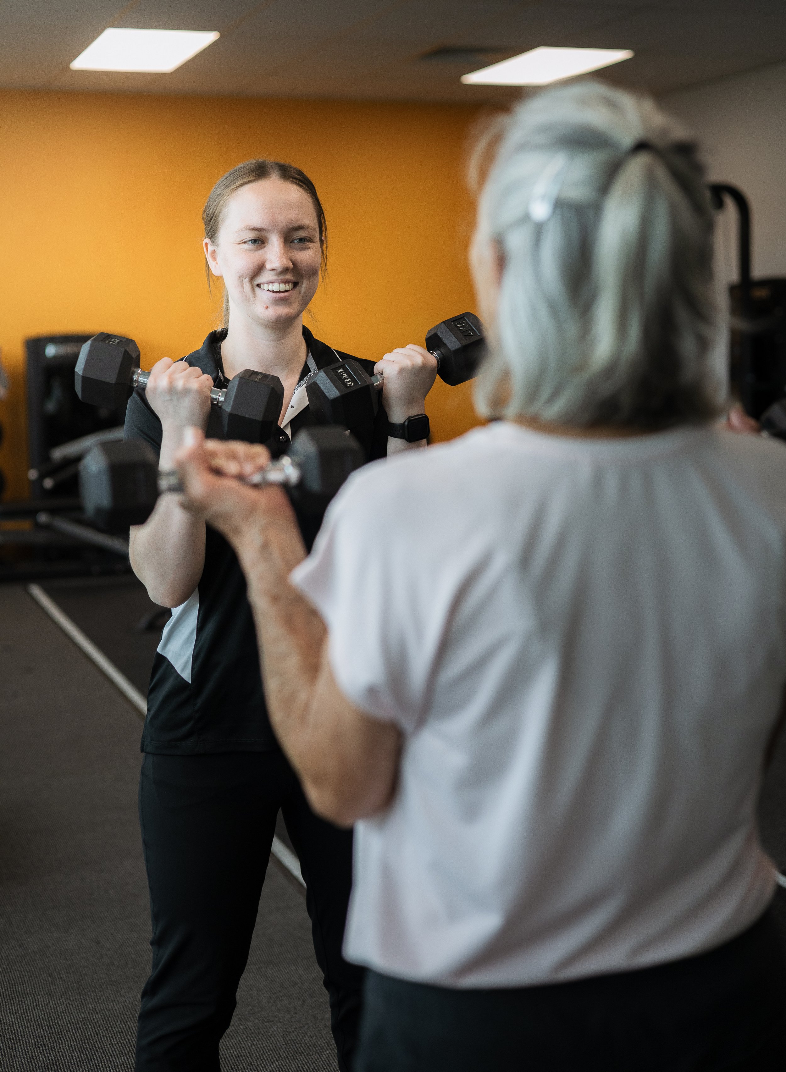 Our Exercise Physiologist Tegan Berry-Smith holding dumbbells taking a client through a Strength For Life Session. Resilient Health Group, 226 Magill Road, Beulah Park SA 5067. Strength For Life Adelaide.
