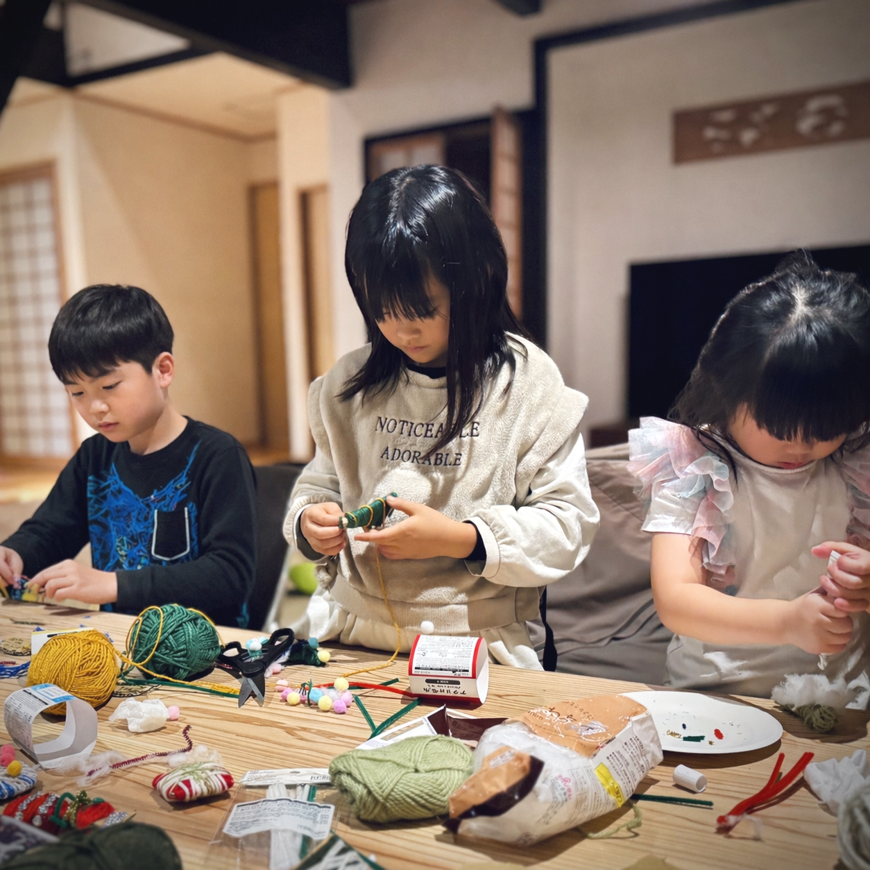 子供たちが毛糸や針を使ってクラフトをしている室内の様子