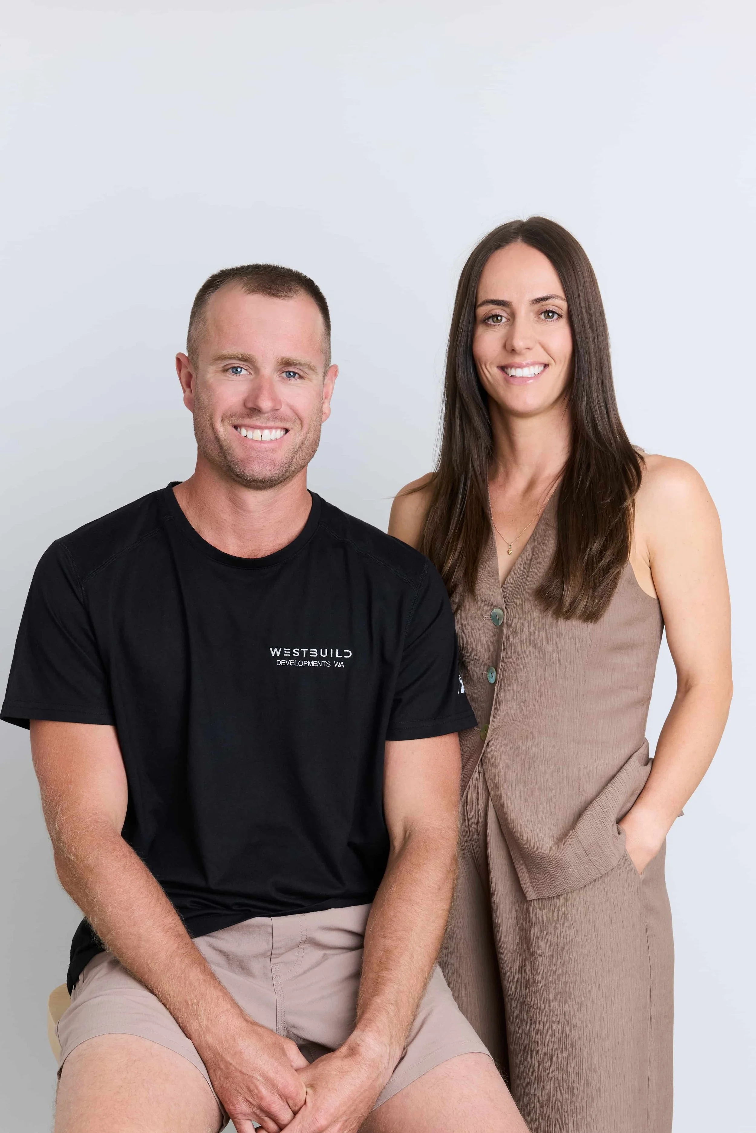 Westbuild Developments WA owners Luke and Sheree posing together in front of a gray background.