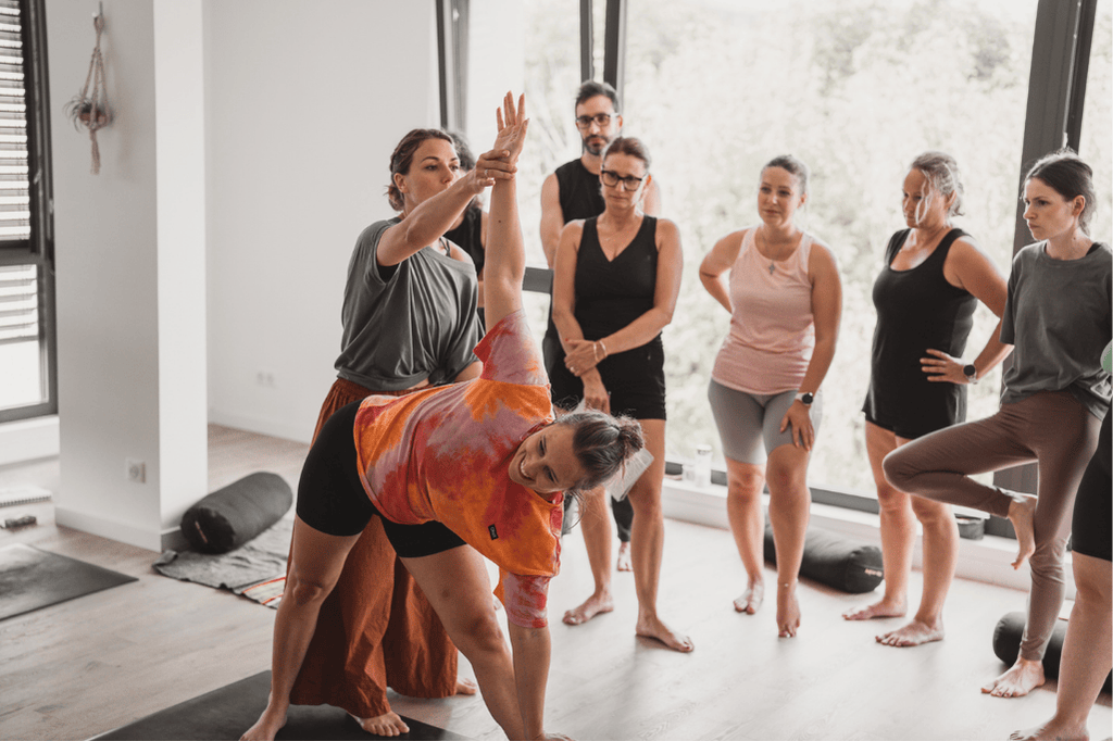 une professeur de yoga en train de montrer comment ajuster la posture de trikonasana, le triangle 