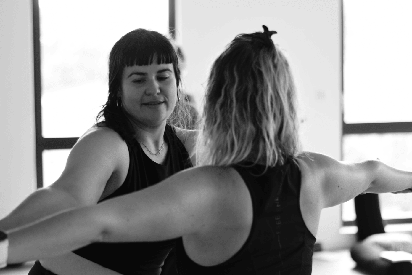 jeune professeur de yoga en train d'ajuster une femme en guerrier 2