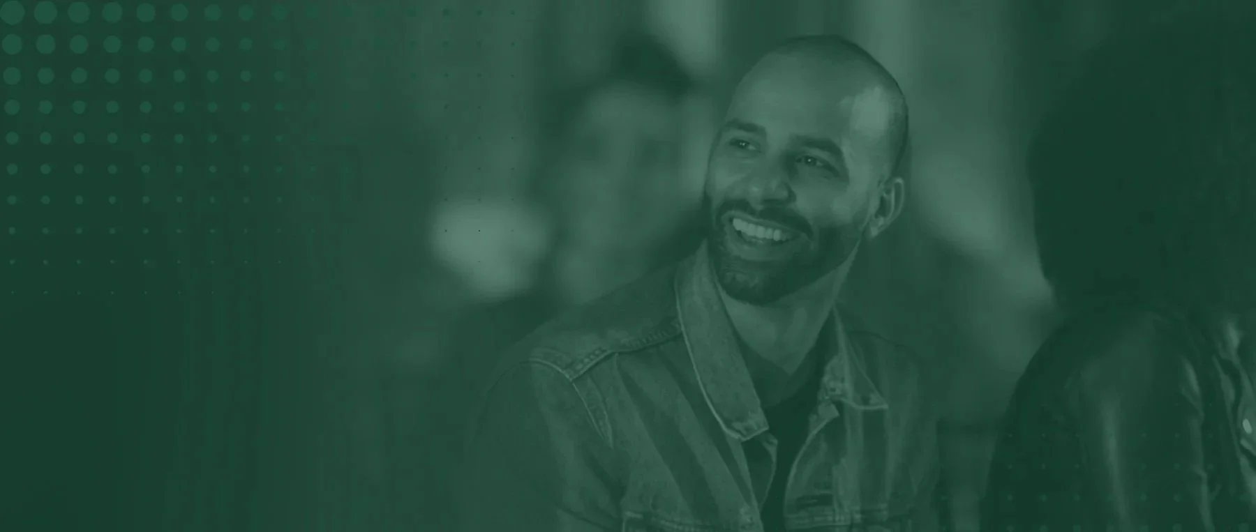 A smiling man with a beard and a shaved head engaging in conversation at a social gathering.