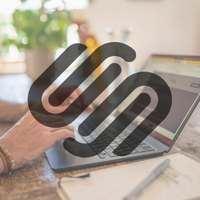 Hand die een laptop gebruikt met grafieken op het scherm, in een thuiskantooromgeving.