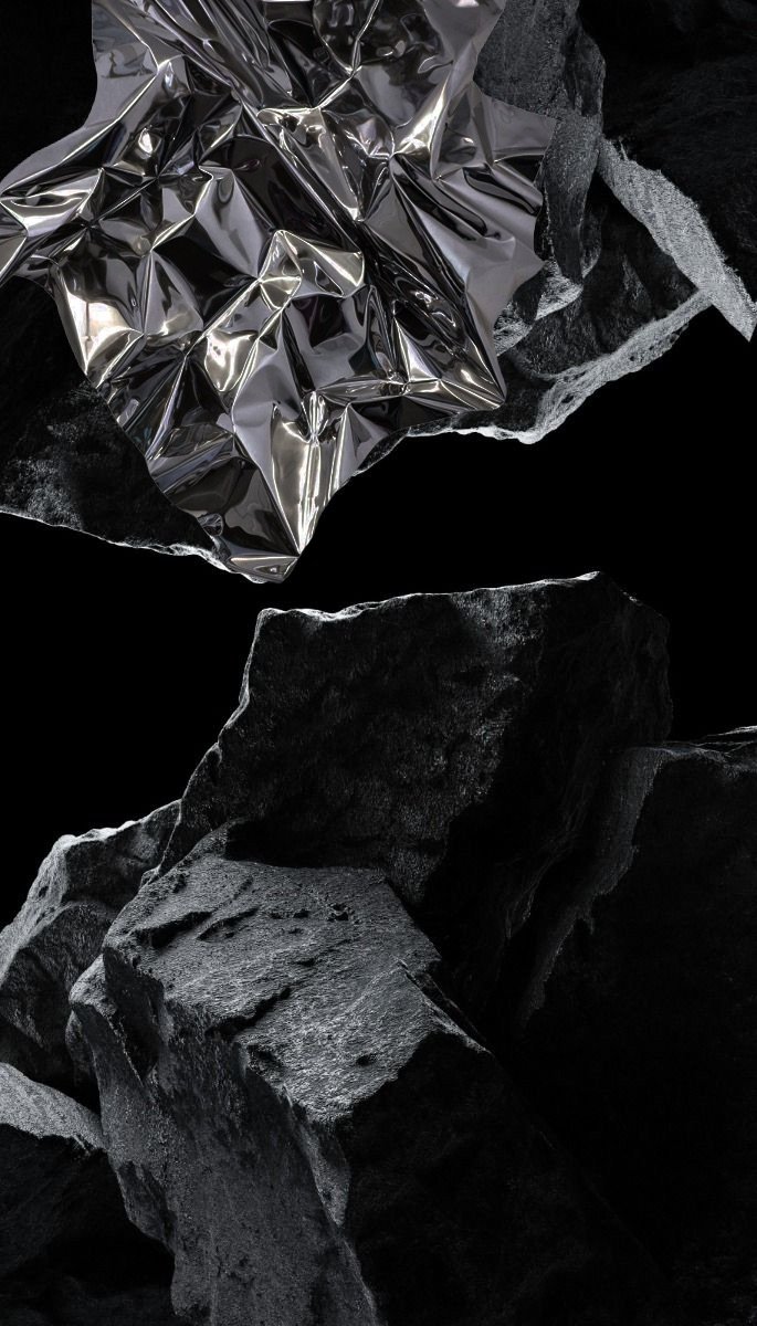A close-up view of black rocks with a piece of crumpled silver foil among them. Architecture and Design by Auliseo (Aurèle Eliseo Stauffer)