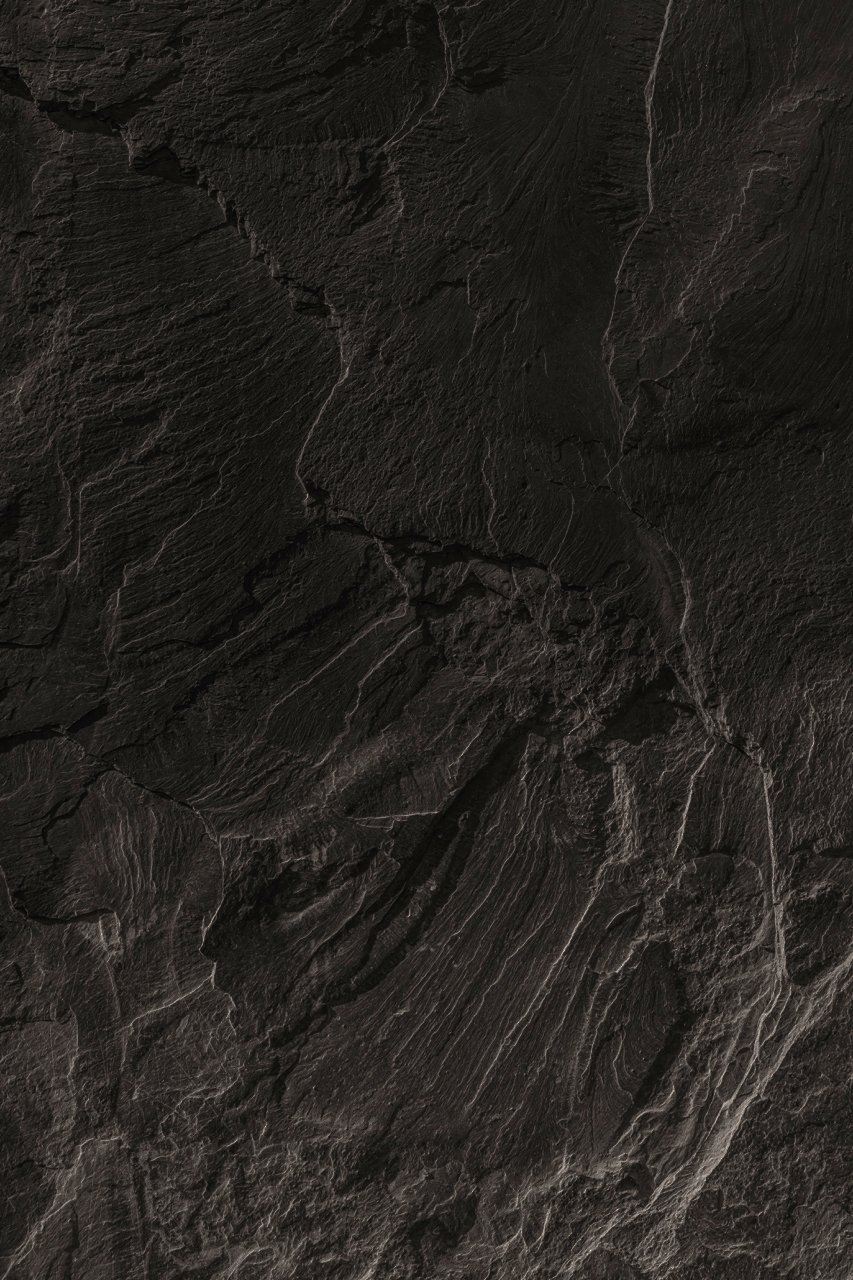 Close-up of a dark, textured stone surface with visible cracks and veining.